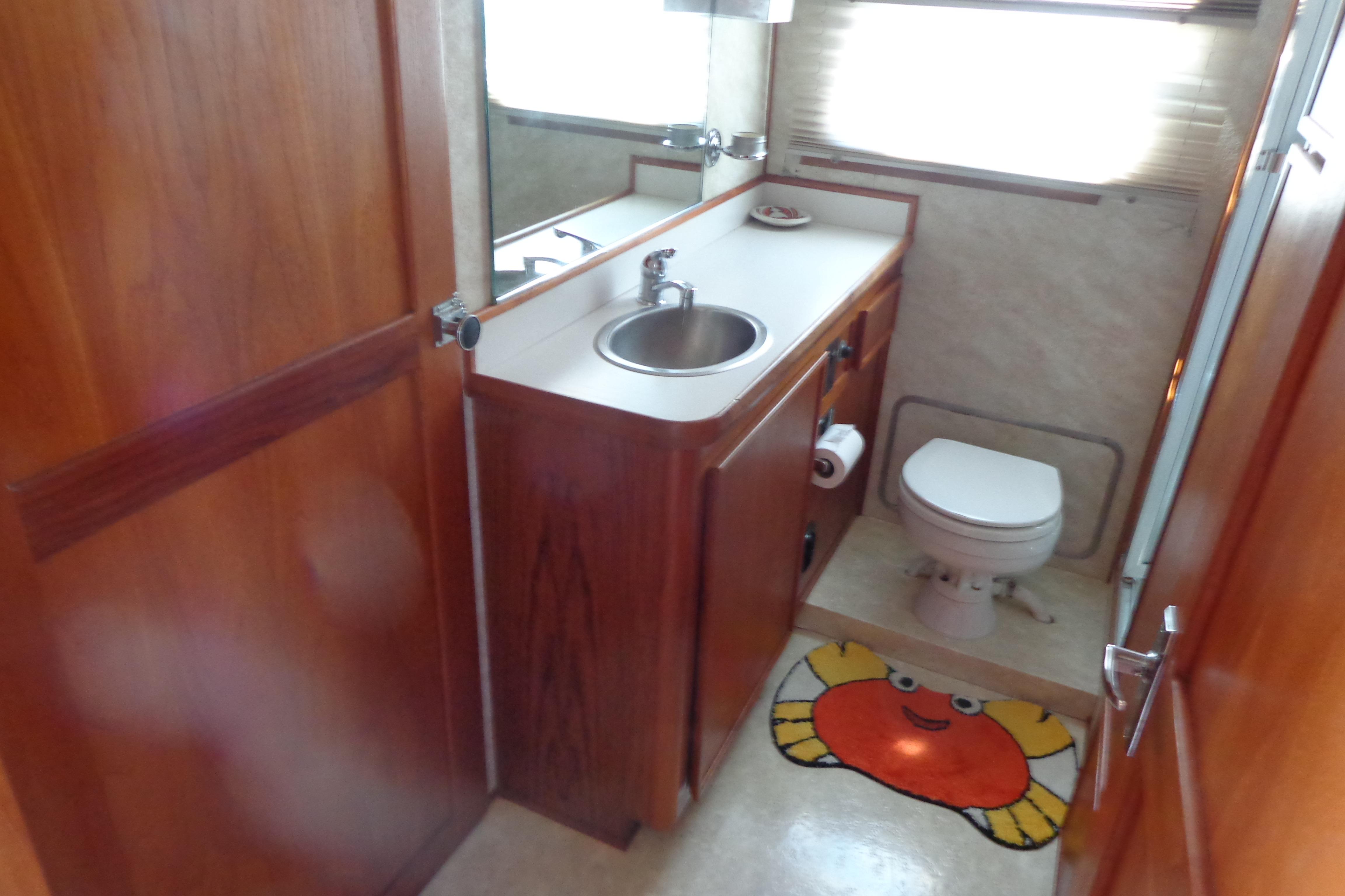 Bathroom interior of 1992 Cruise-A-Home Corsair 4200 with sink, toilet, and crab-themed mat.