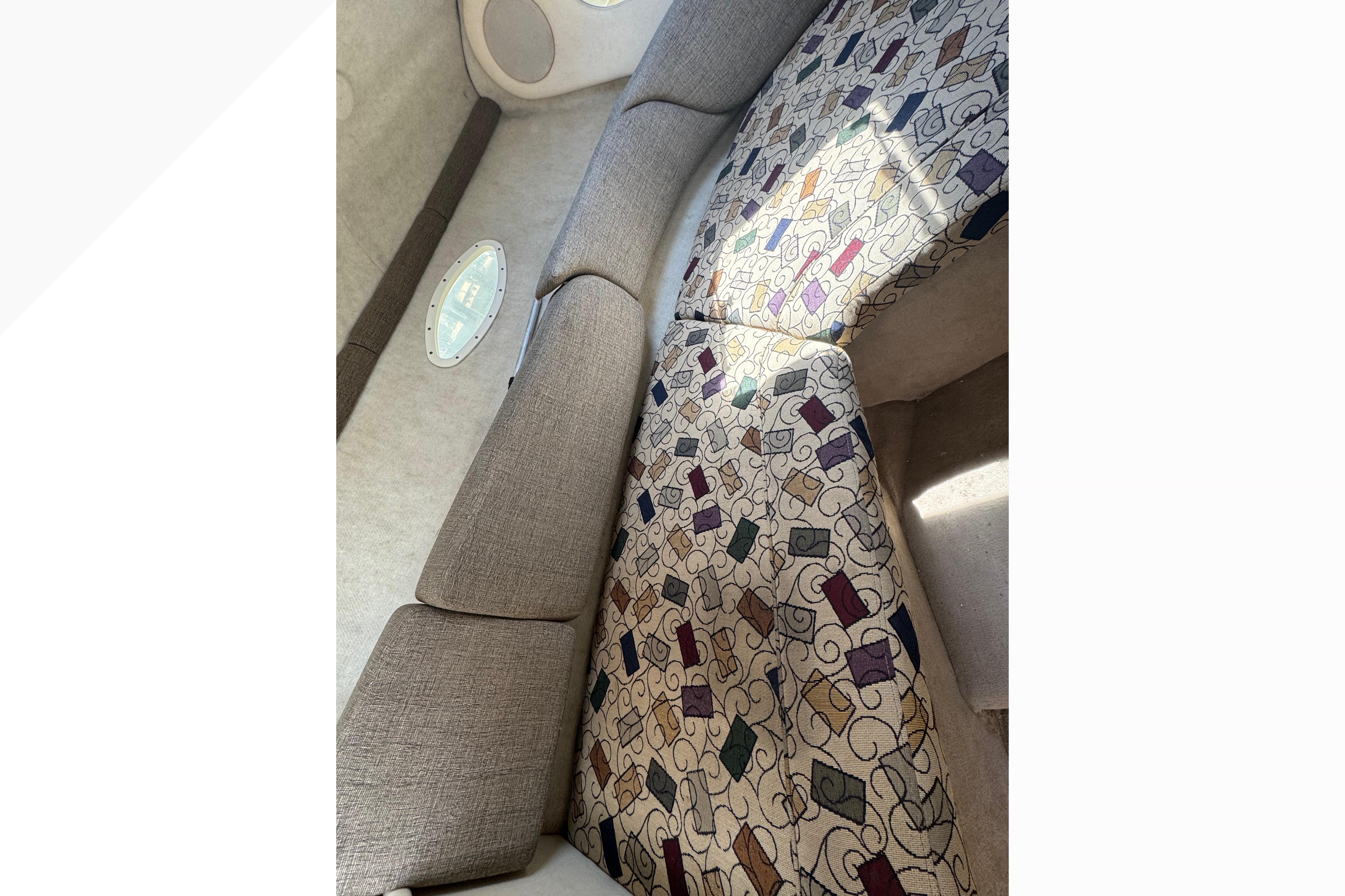Interior of 2001 Sea Ray 245 Weekender with patterned upholstery and porthole window.