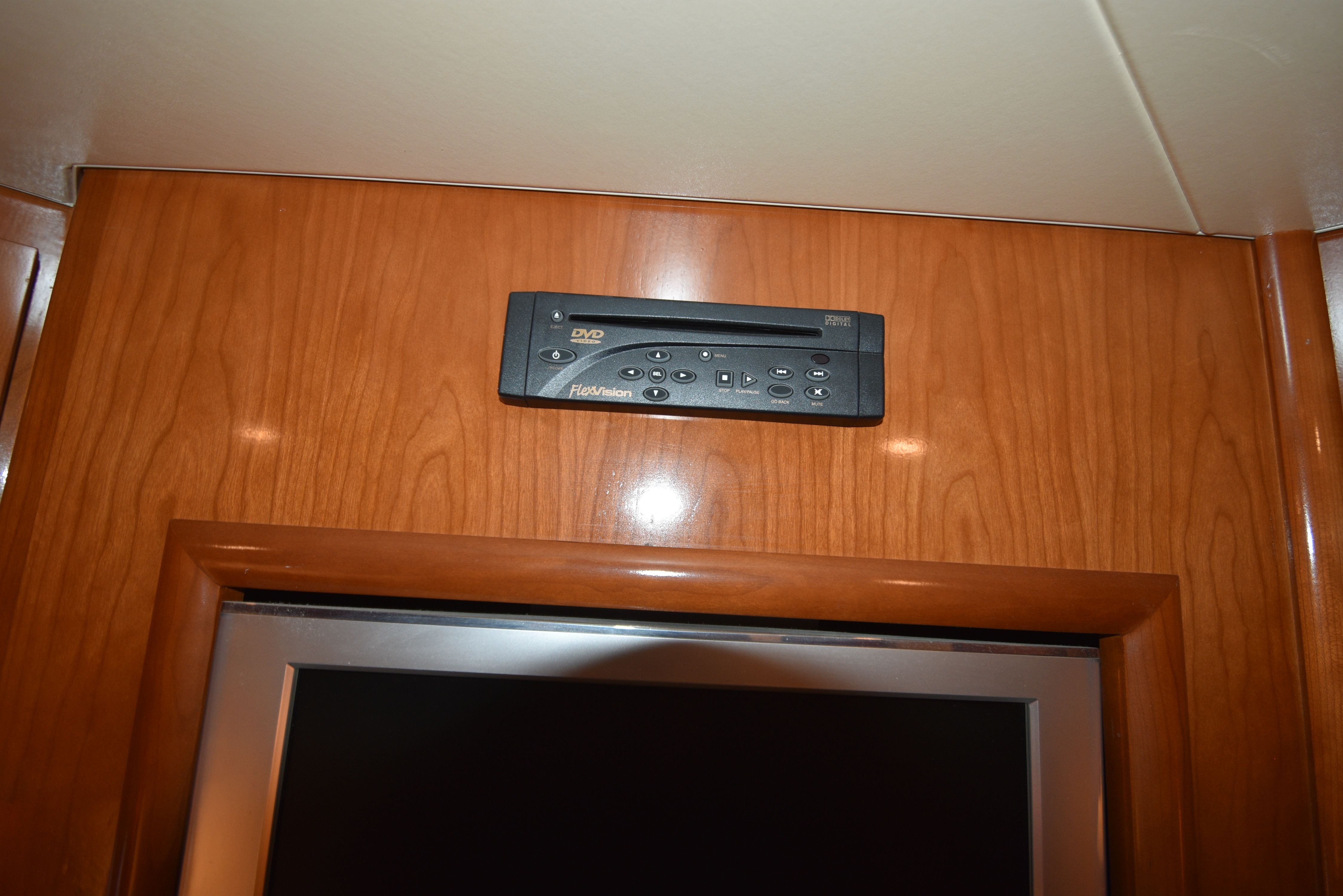 A DVD player is embedded in wood paneling above a screen.