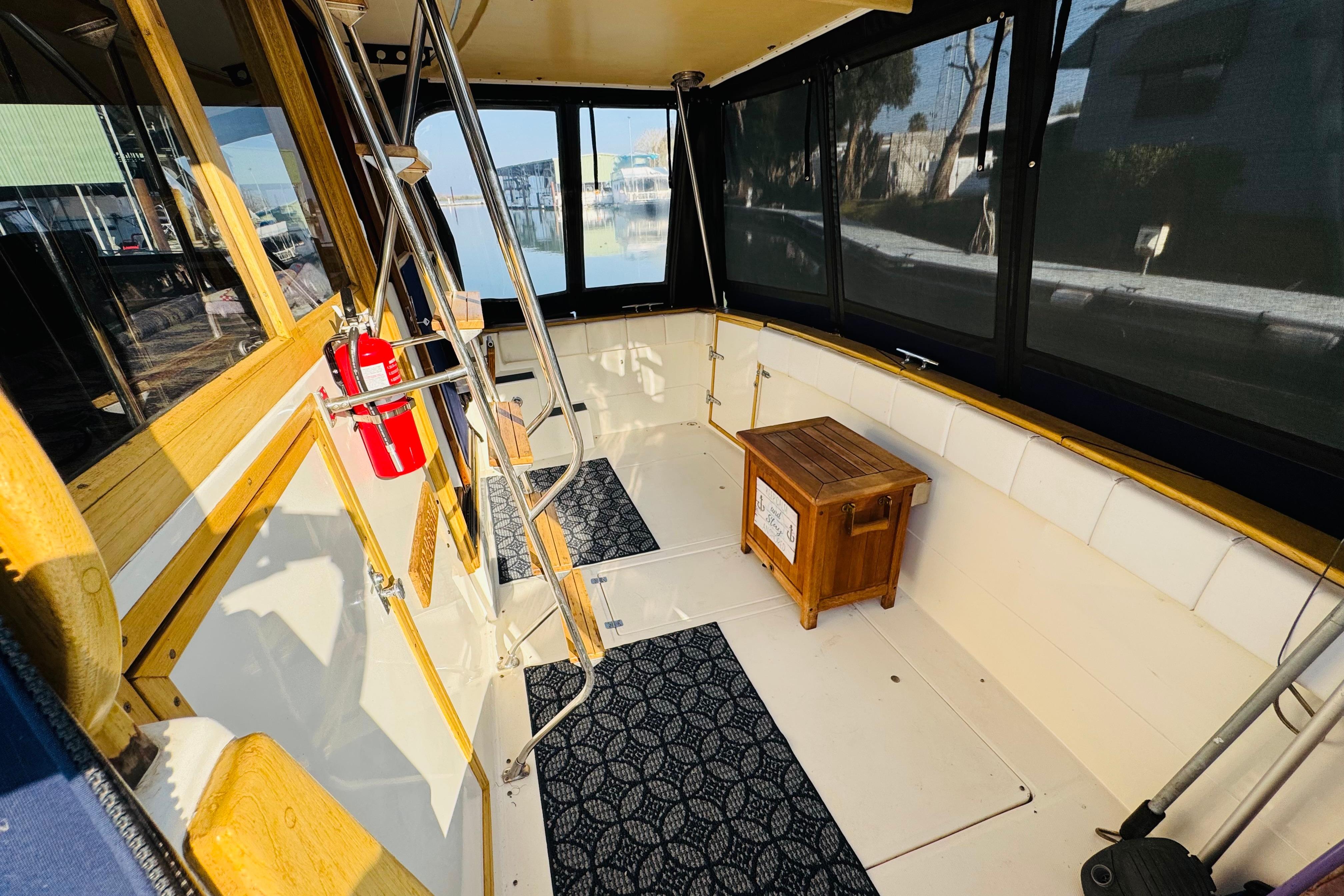 1990 Bayliner 3888 Motoryacht interior with seating, wooden accents, and a fire extinguisher.