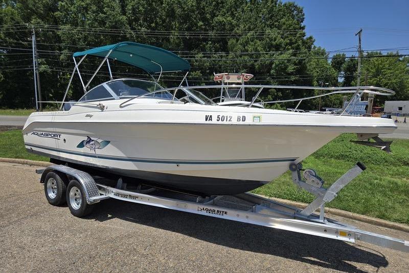 2004 Aquasport 215 Osprey Sport boat on trailer, parked outdoors.