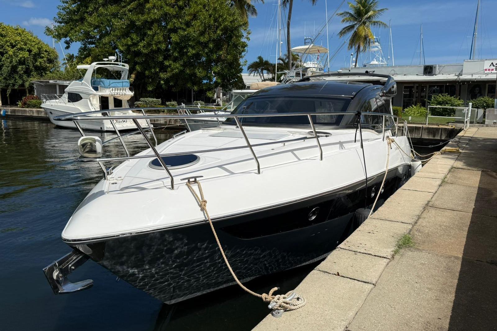 2023 Schaefer 400 Sport yacht docked by a marina, surrounded by lush greenery.