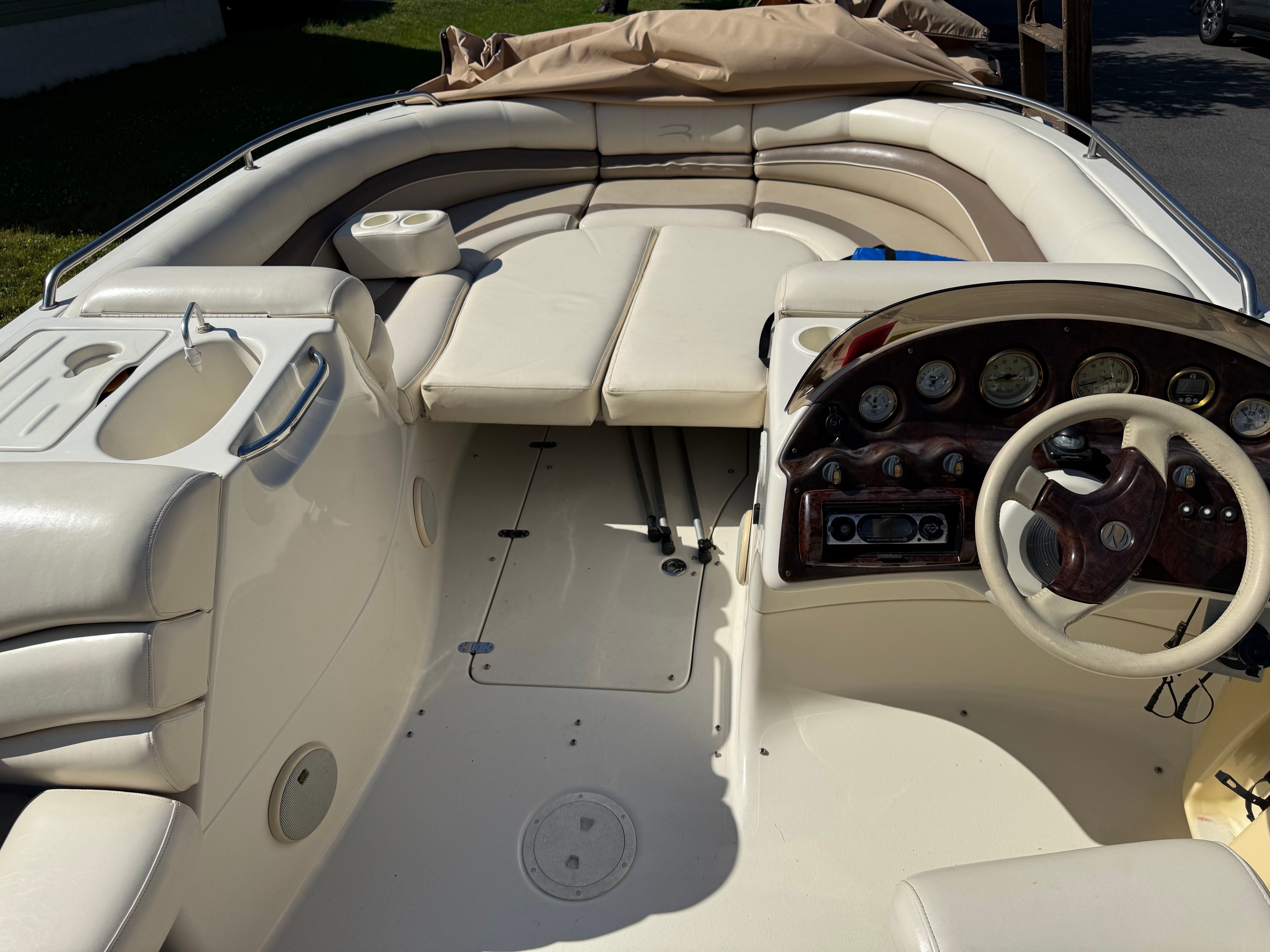 Interior of a Bennington RL210 boat with cream-colored seating and a sleek dashboard.