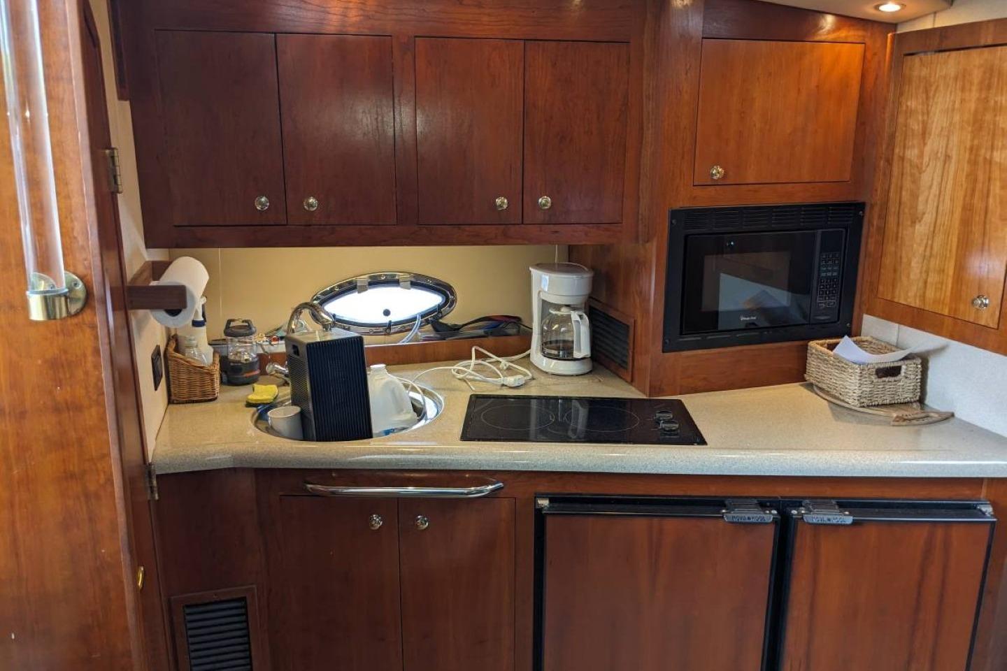 2003 Cruisers 3970 yacht kitchen with wooden cabinets, stove, microwave, and coffee maker.