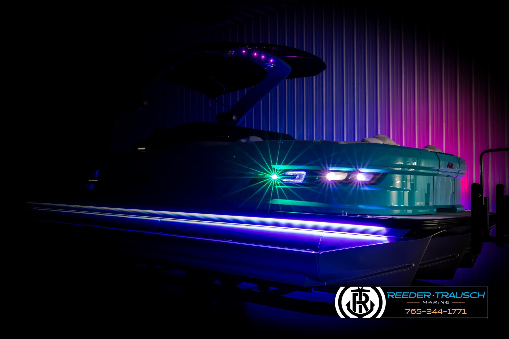 2025 Avalon 2585 Excal VRBW pontoon boat with vibrant LED lighting in a dark setting.