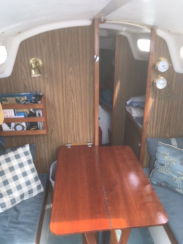 Interior of a 1975 O'Day Sloop with wooden table and cushions.