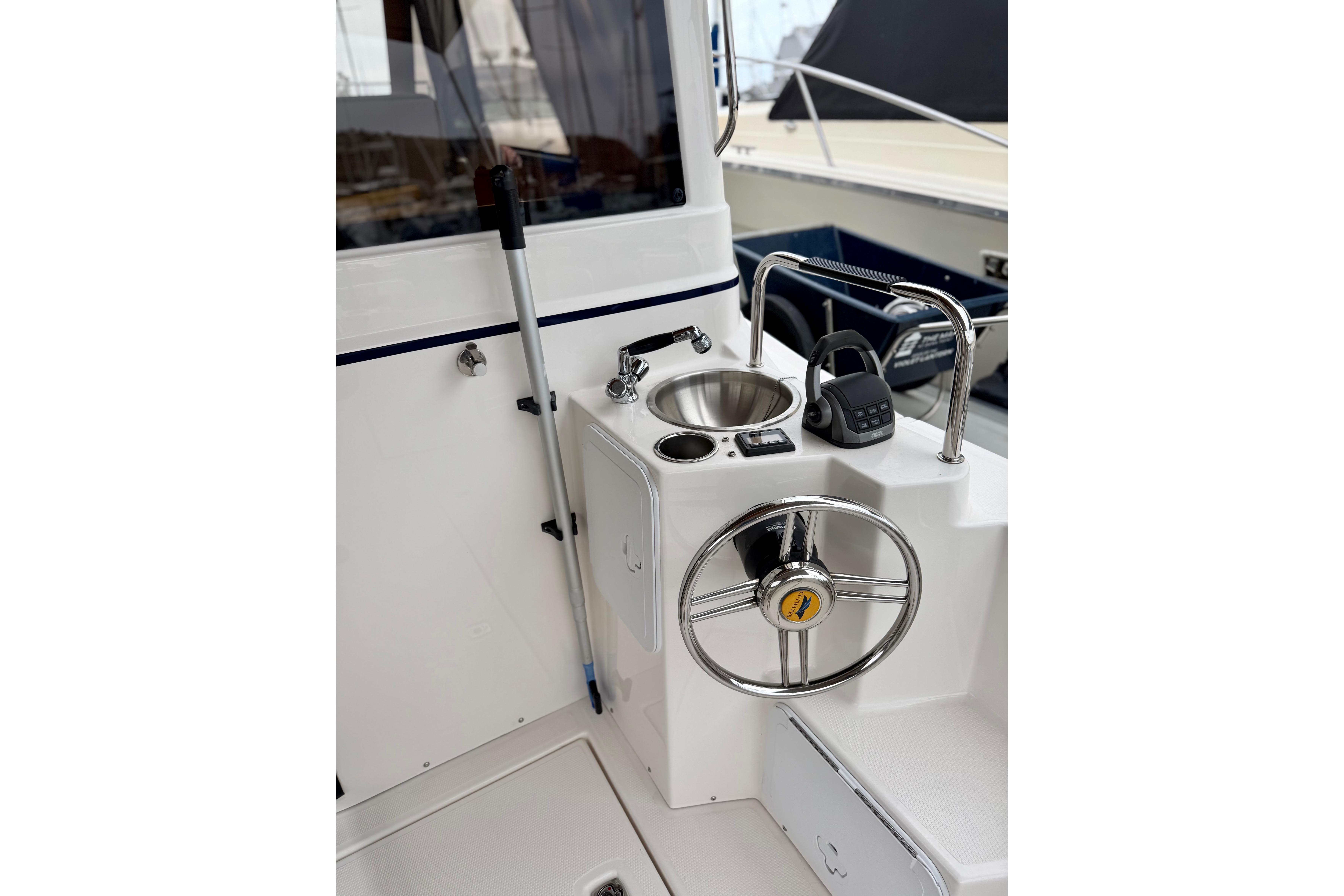 2021 Cutwater C-28 boat helm with steering wheel, sink, and controls.