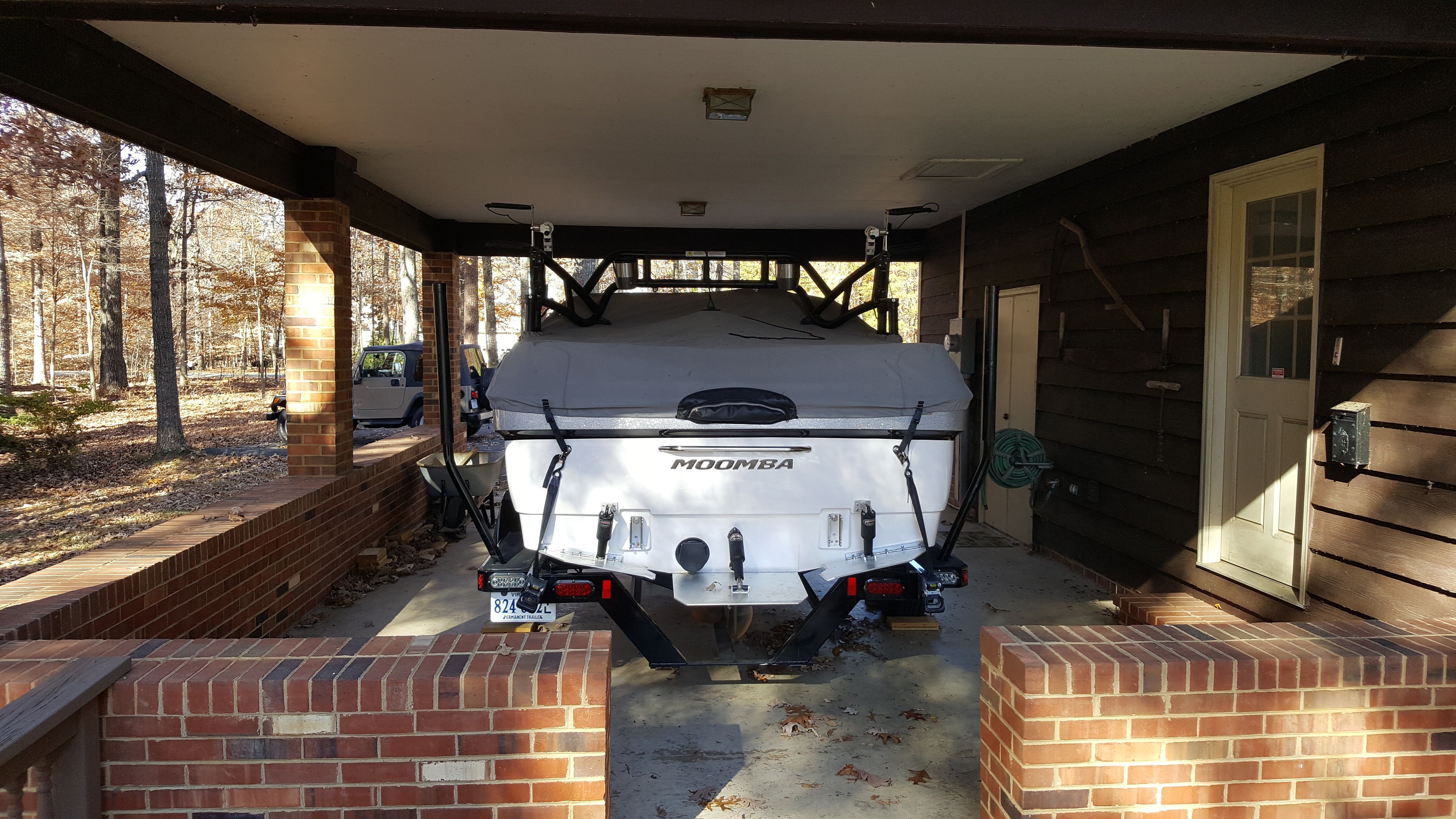 A 2016 Moomba Mondo boat is parked under a carport, surrounded by brick walls.