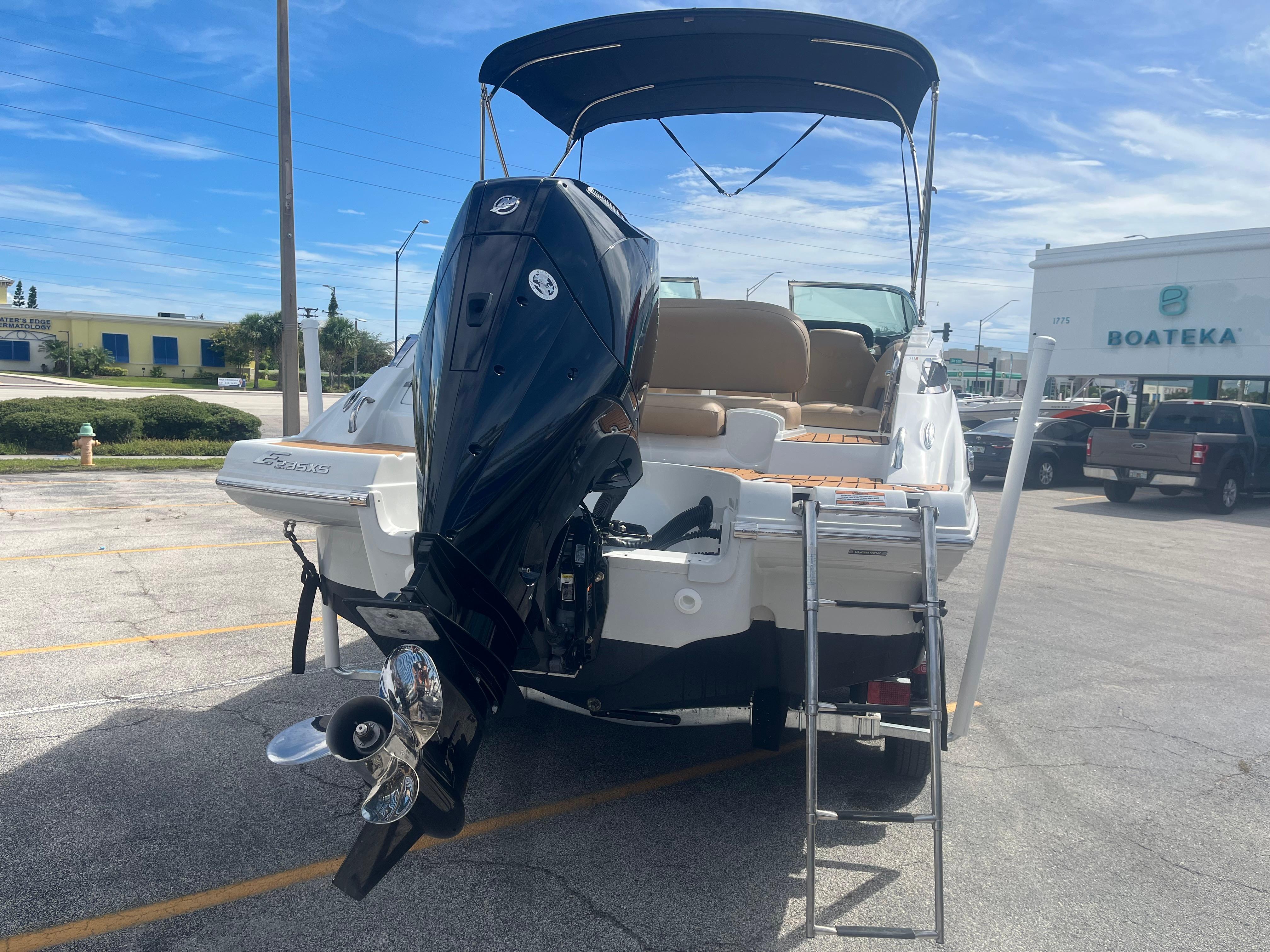 2022 Crownline Eclipse E235 XS boat with outboard motor and swim ladder in a parking lot.
