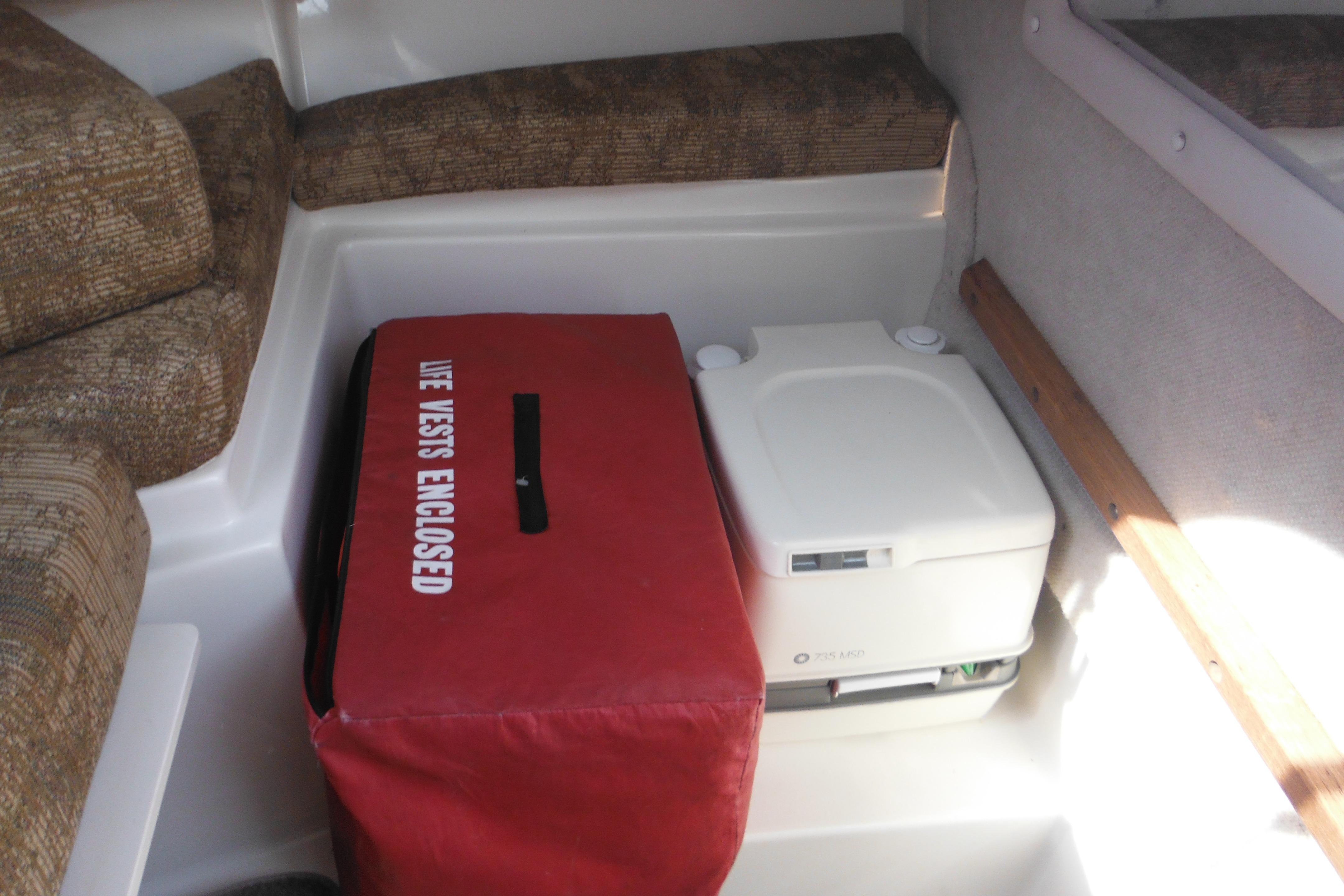Interior of 2005 Seaswirl Striper 2101 with life vest storage and portable toilet.