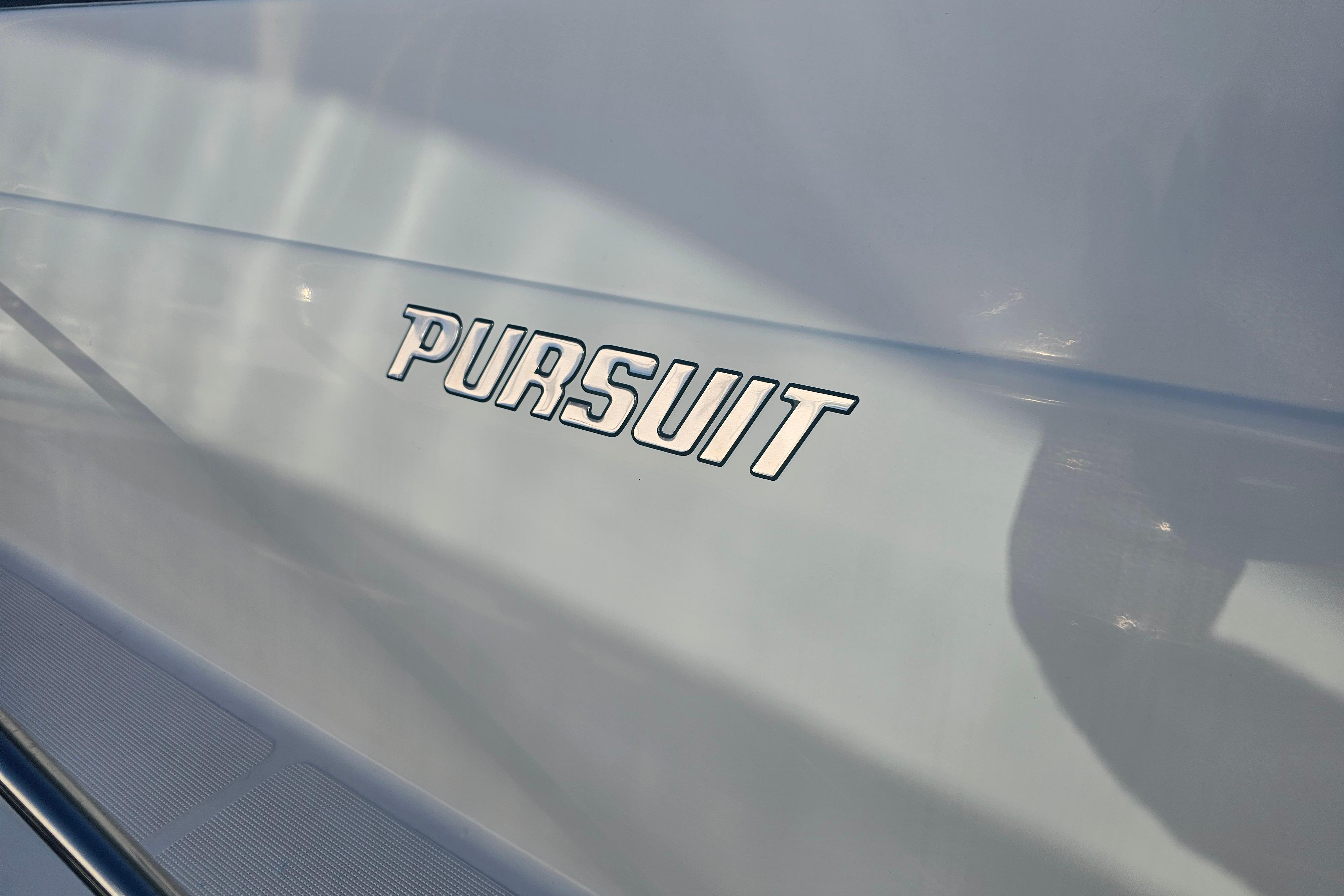 Close-up of 2001 Pursuit 3000 Express boat logo on sleek surface.