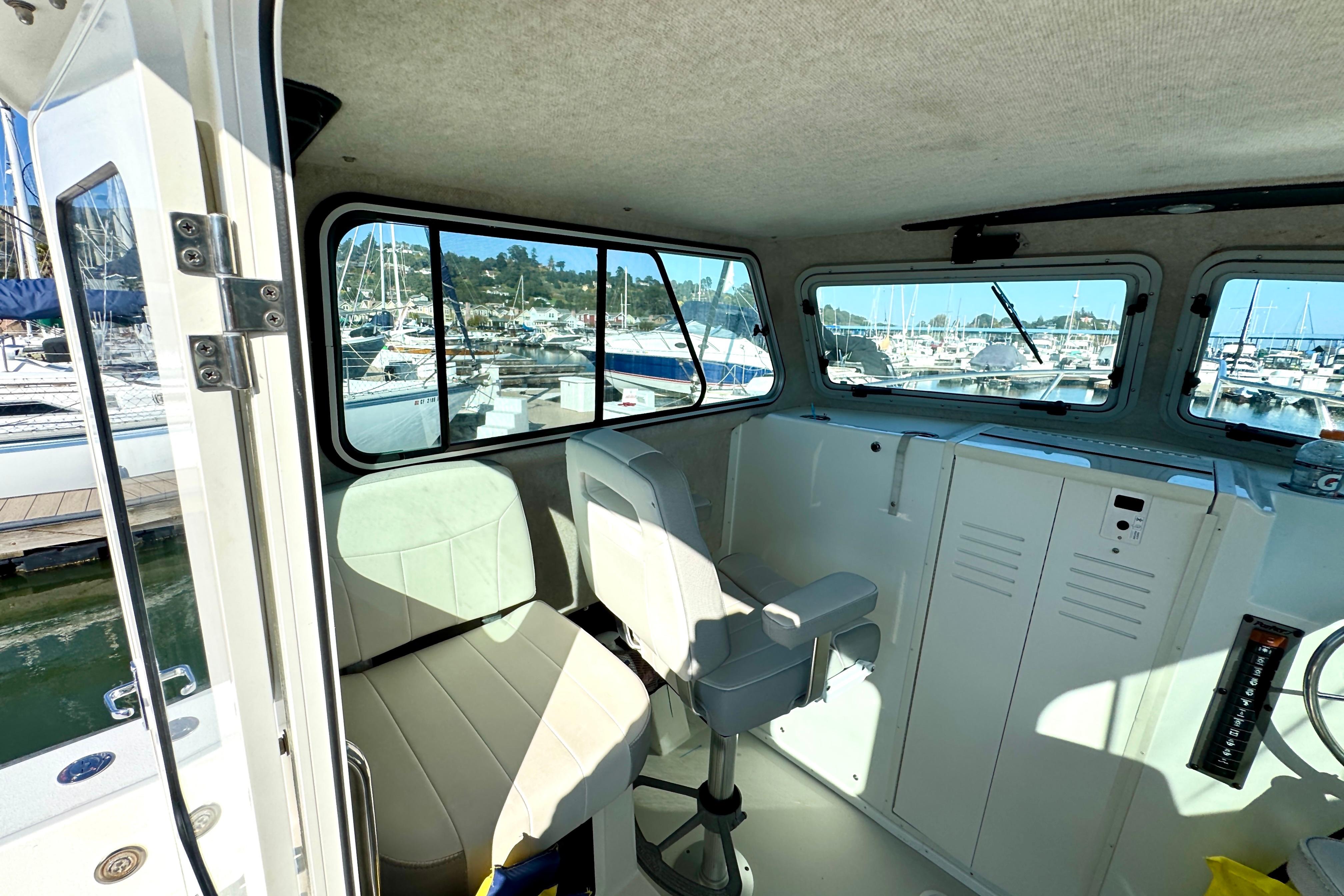 Interior of 2021 Parker 2820 XLD Sport Cabin boat at marina, featuring seating and windows.