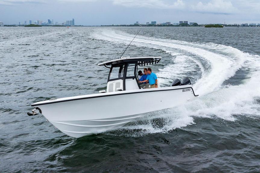2027 Reef Runner 280 boat cruising on open water with city skyline in background.