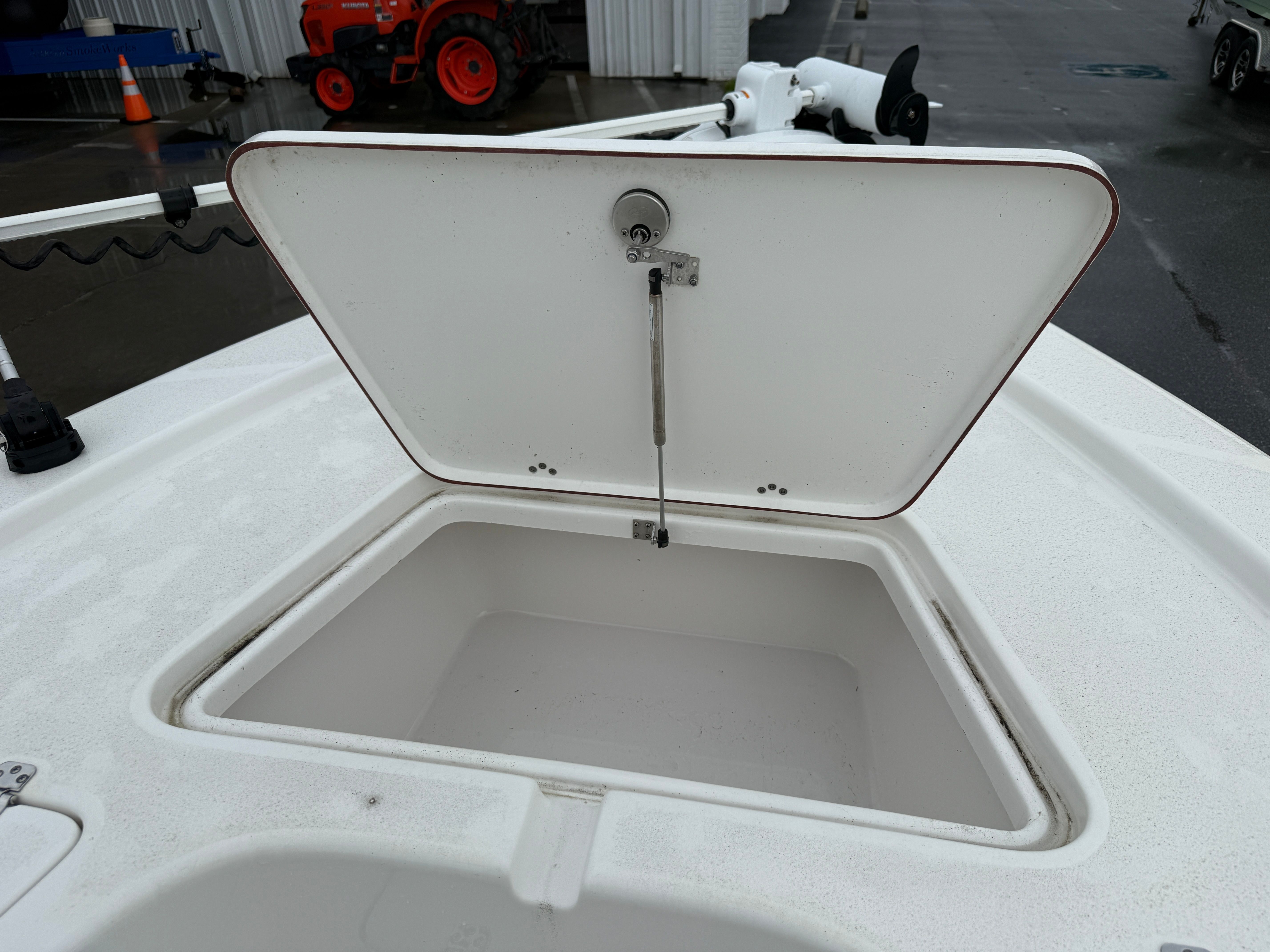An open storage compartment on a boat with a white lid.