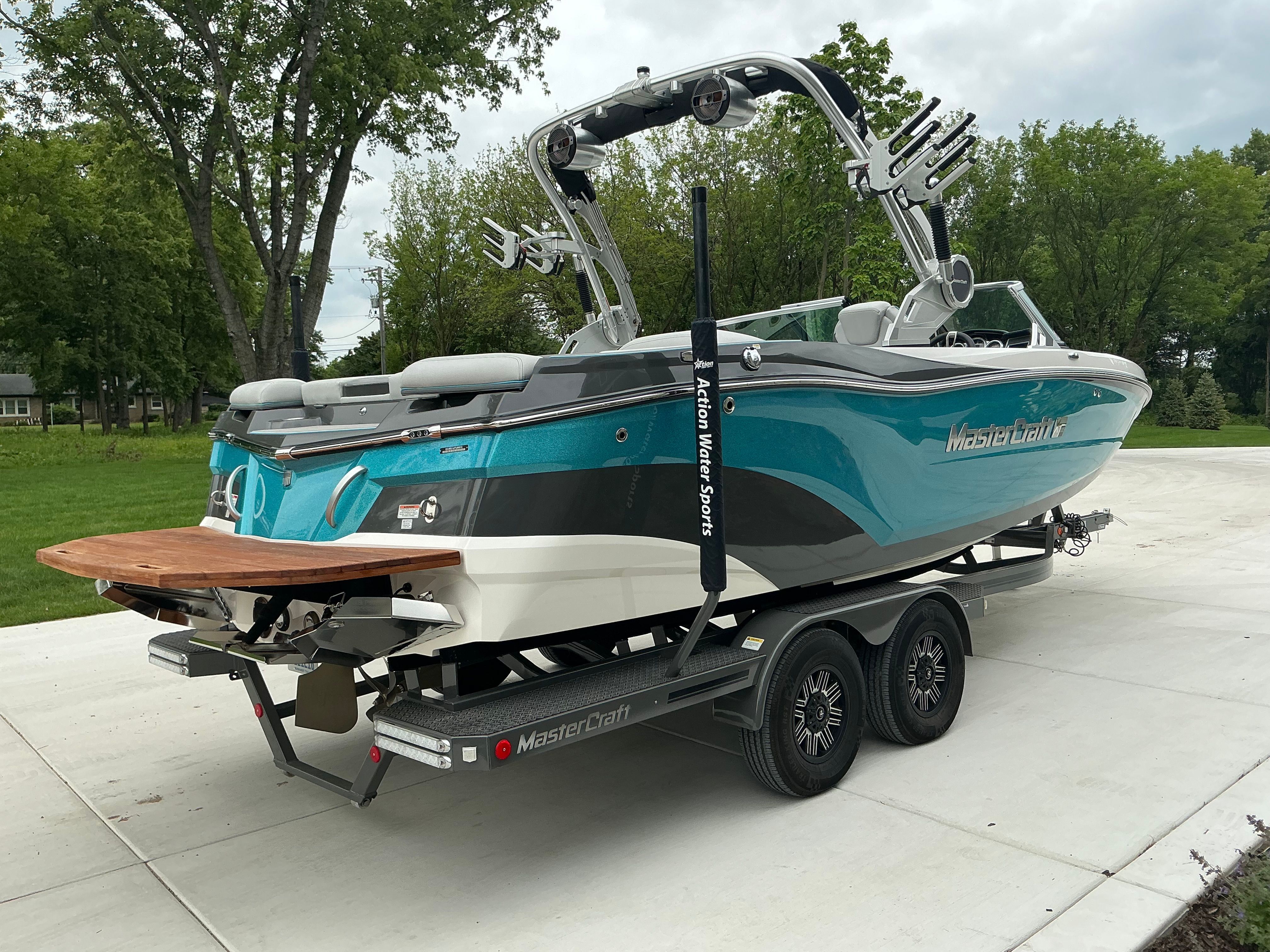 A turquoise 2019 MasterCraft XT22 on a trailer, parked on a paved area.