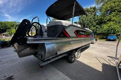 2027 Manitou 25 Encore RF pontoon boat on trailer, parked outdoors.