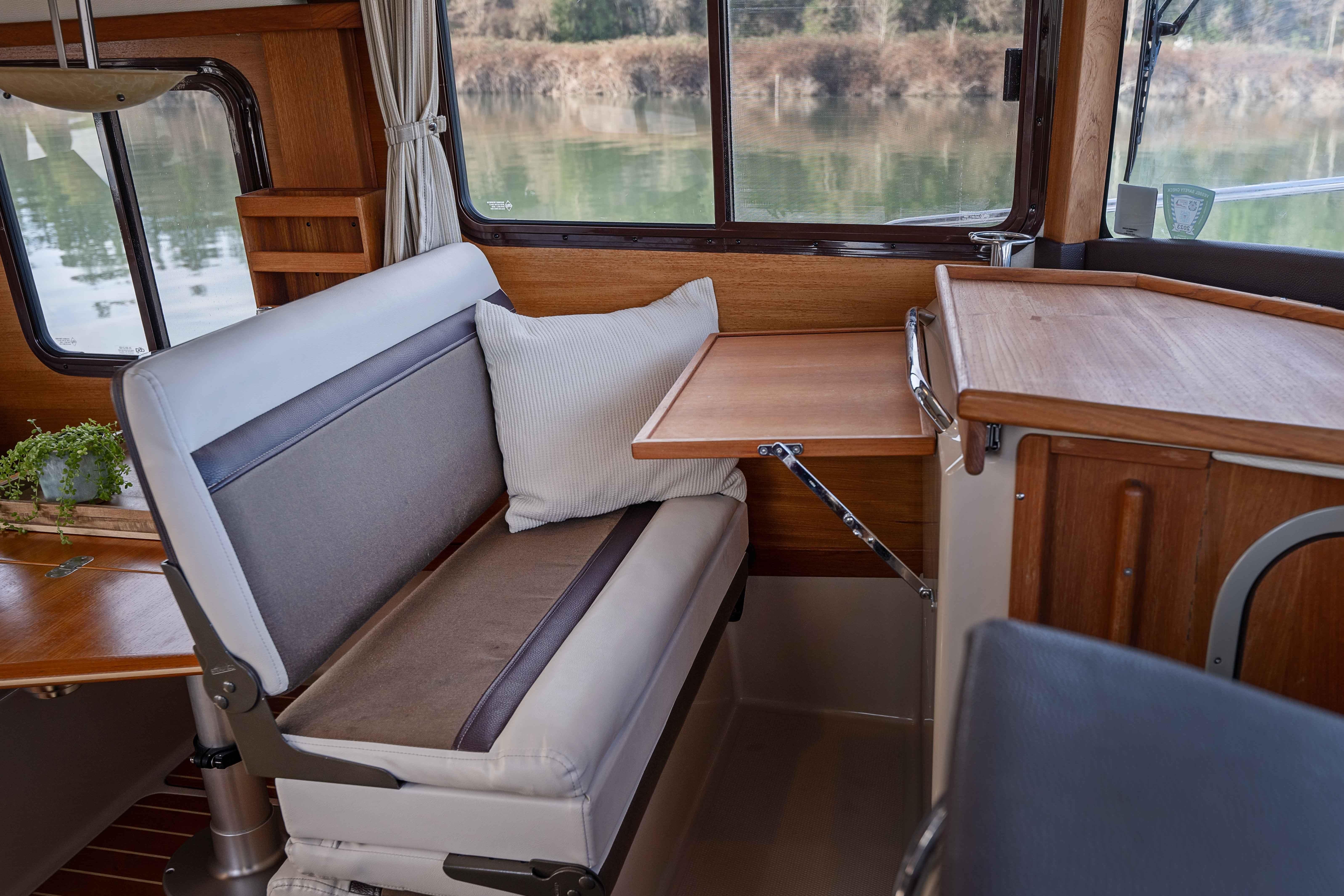 Interior of 2014 Ranger Tug R-31 CB with wooden table and cushioned seating.