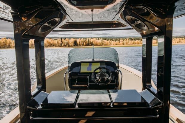 The cockpit of a modern boat with a sleek steering wheel and digital display.