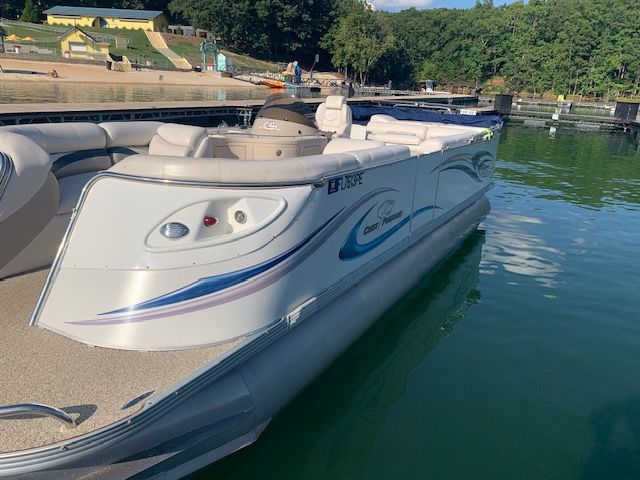 A silver 2007 Crest Savannah pontoon boat sits on calm water.