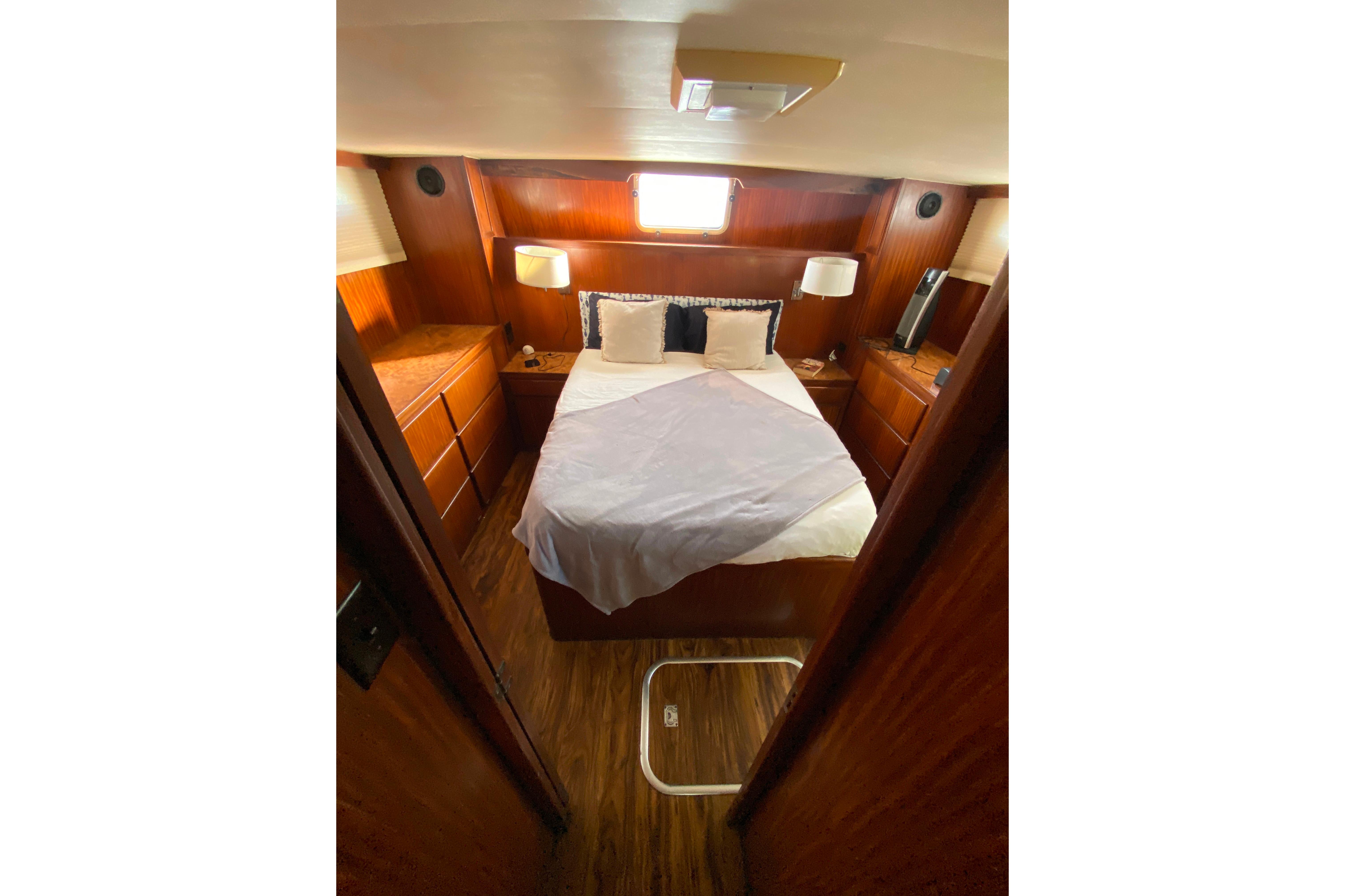 Cozy cabin interior of 1988 Hatteras 40 Double Cabin yacht with bed and wooden furnishings.