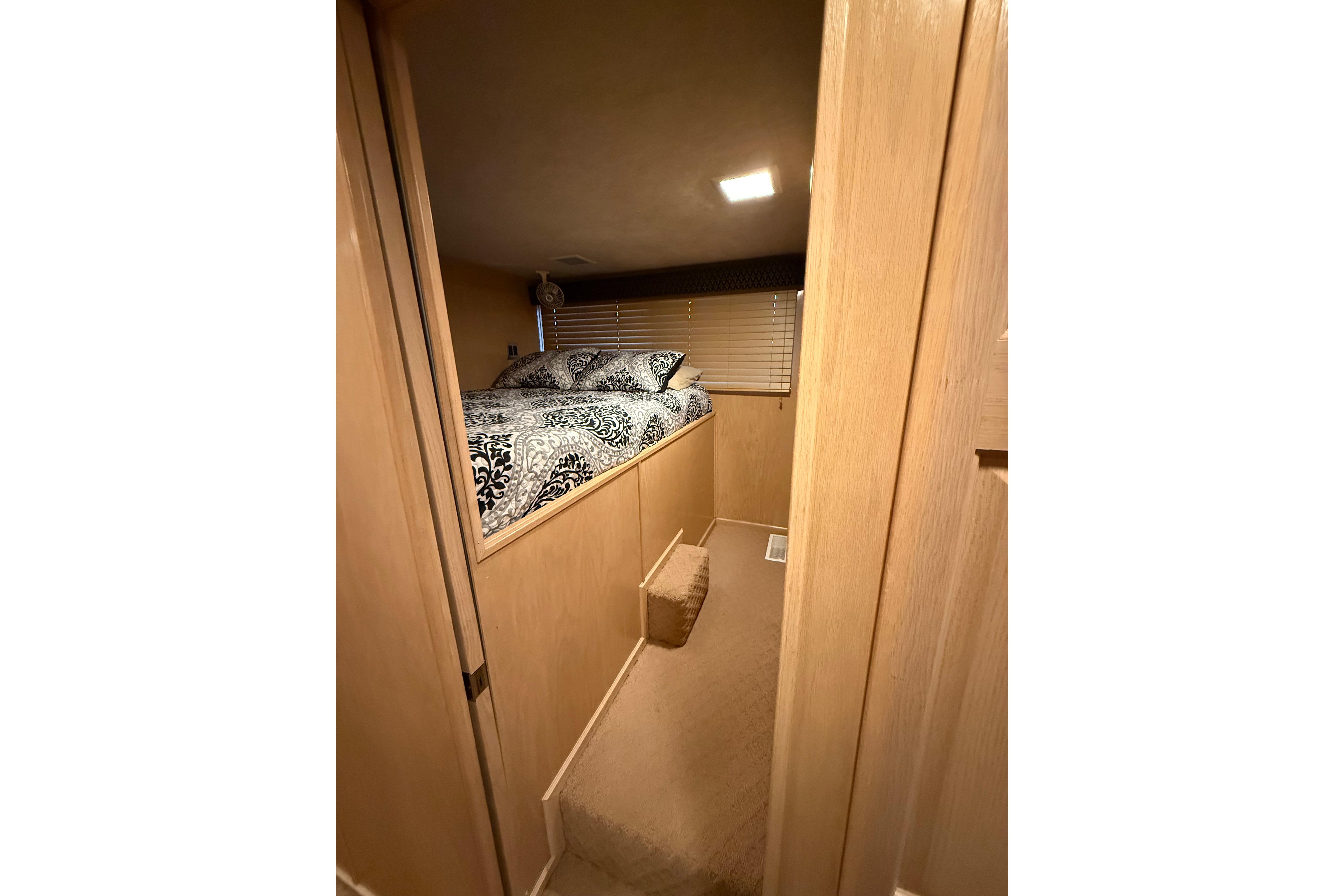 Cozy bedroom interior of 1998 Sumerset 16x76 houseboat with patterned bedding and wooden decor.