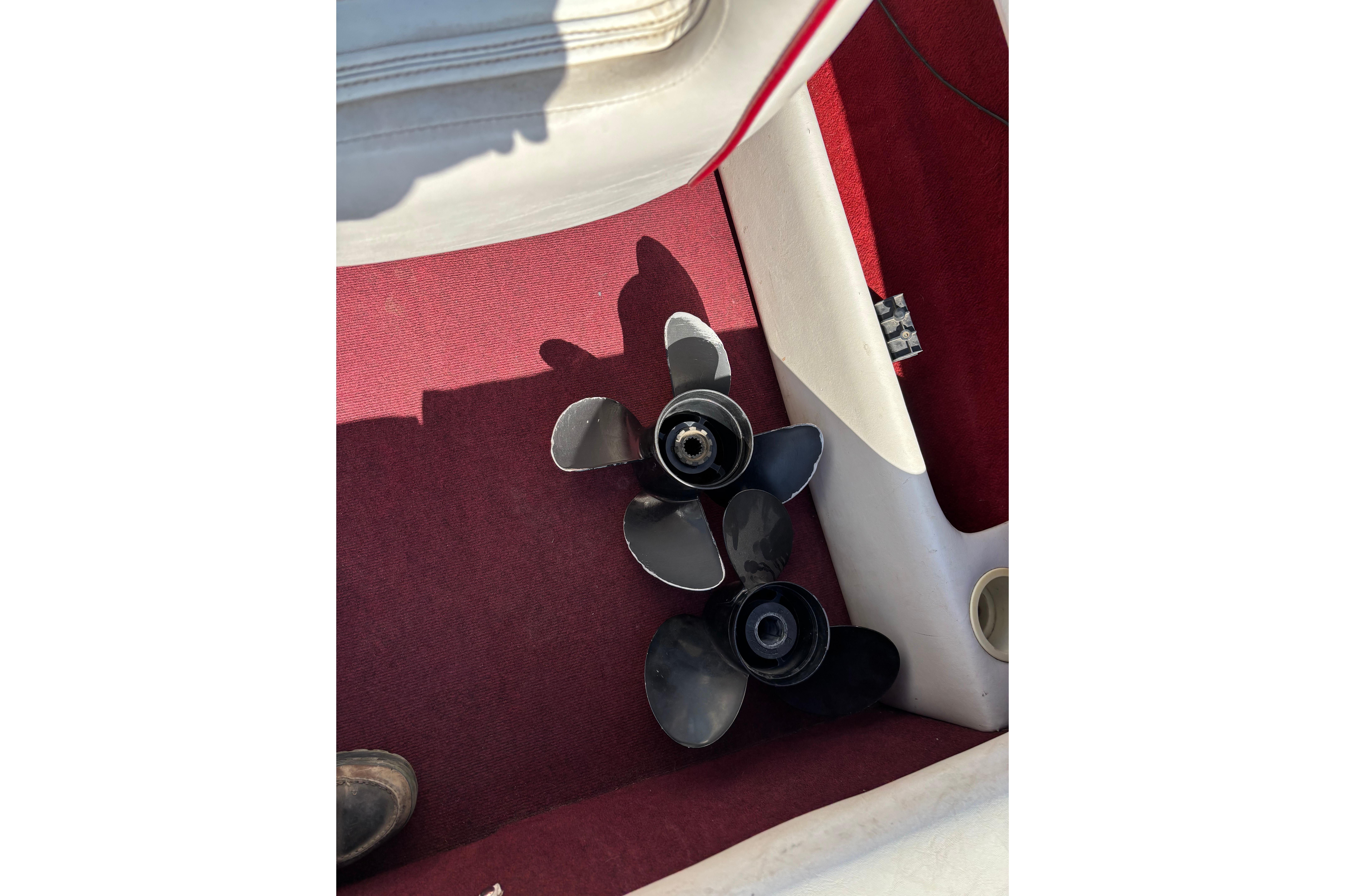 Propellers on red carpet inside 1993 Larson SEi 200 Cuddy I/O boat.