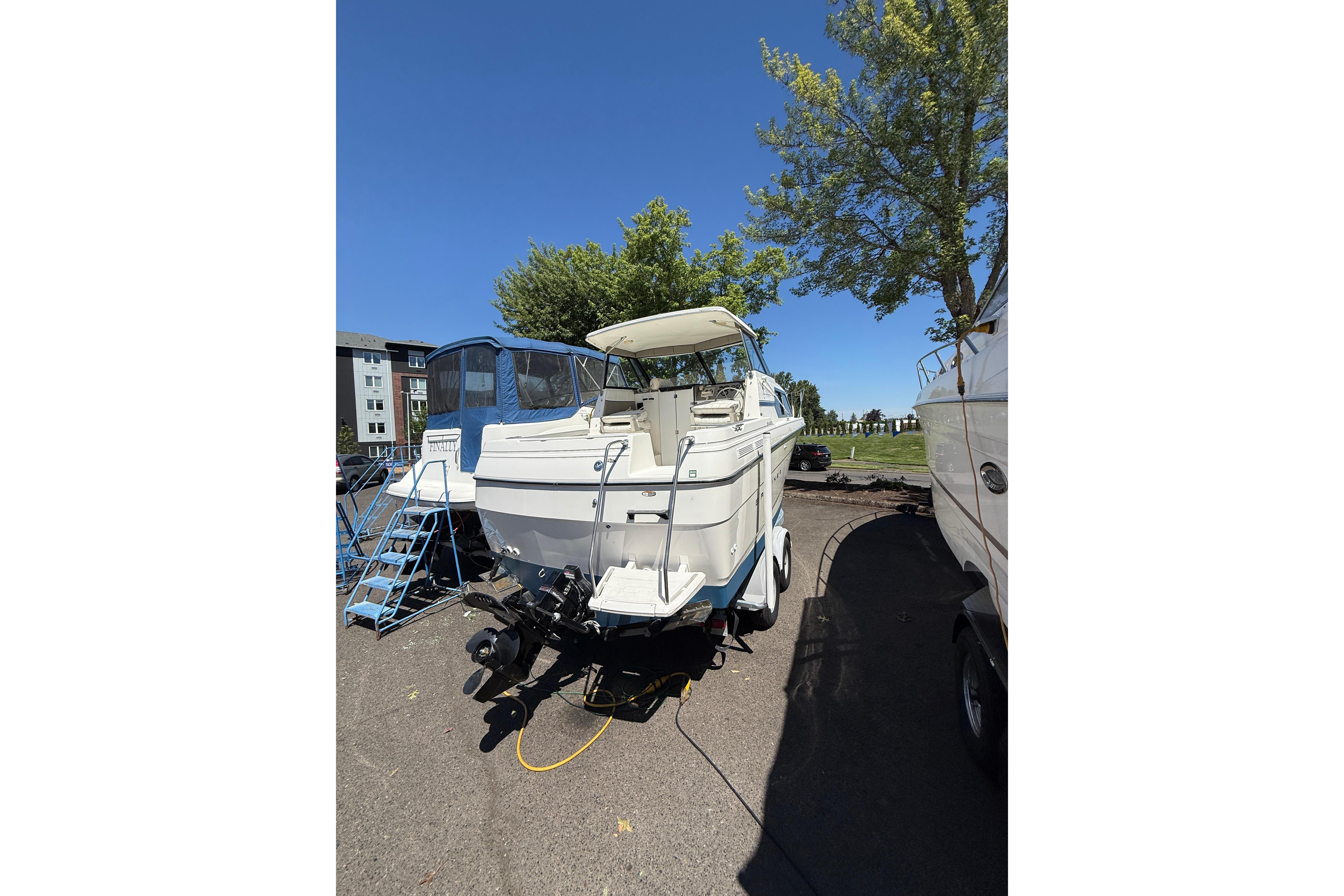 1997 Bayliner 2452 Ciera Express boat on trailer, parked outdoors under clear sky.