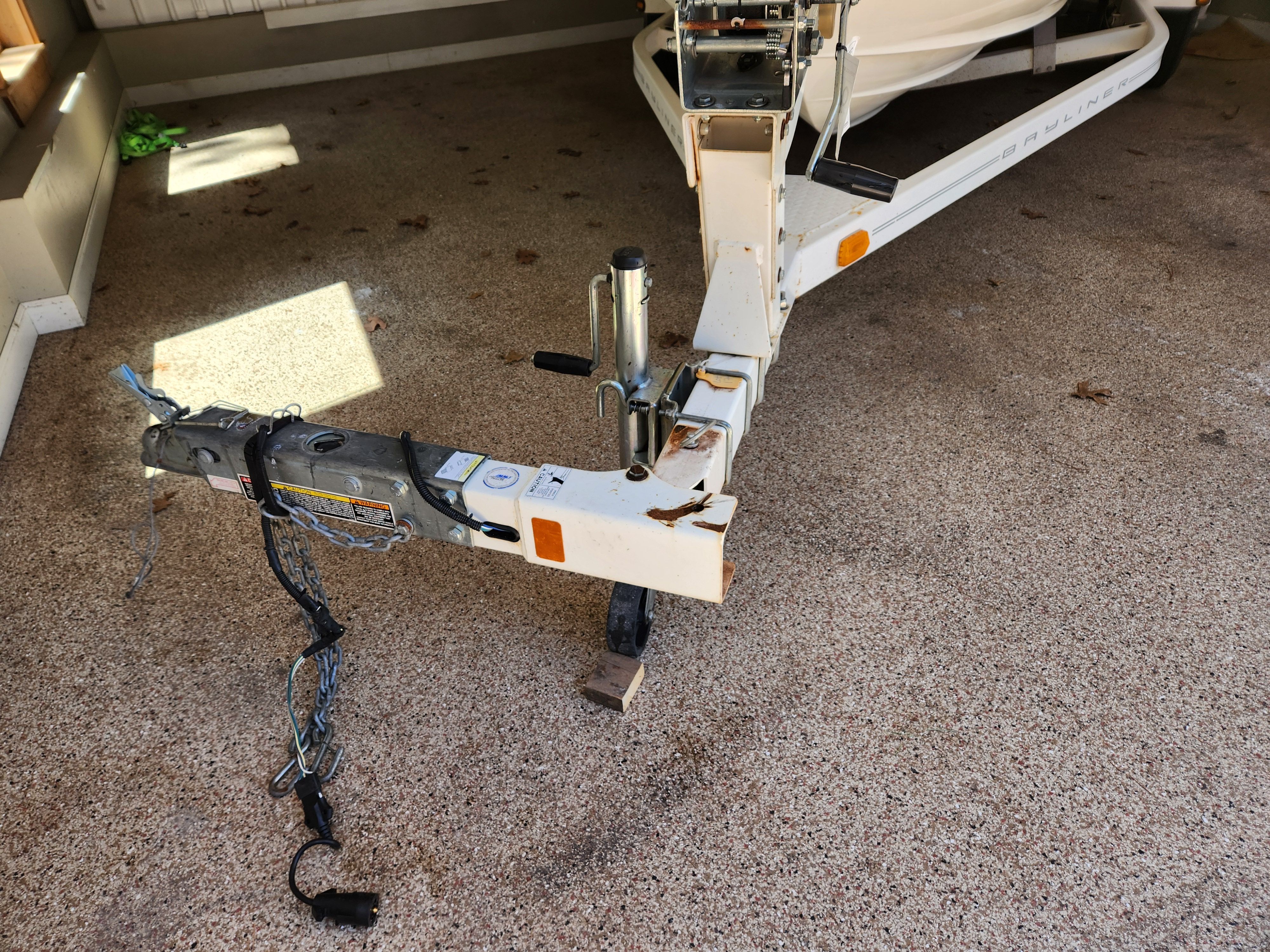 Close-up of a boat trailer with worn cable and support wheel.