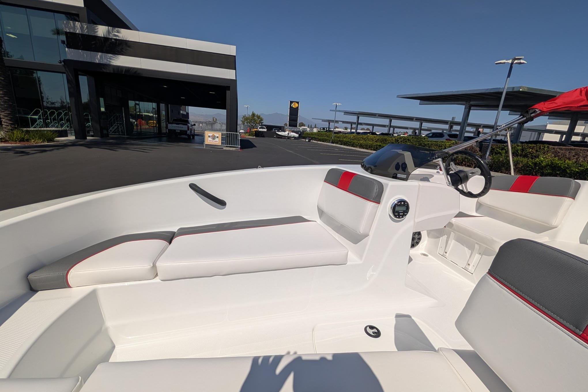 2026 Tahoe T16 boat interior with modern seating and steering, parked outside a showroom.