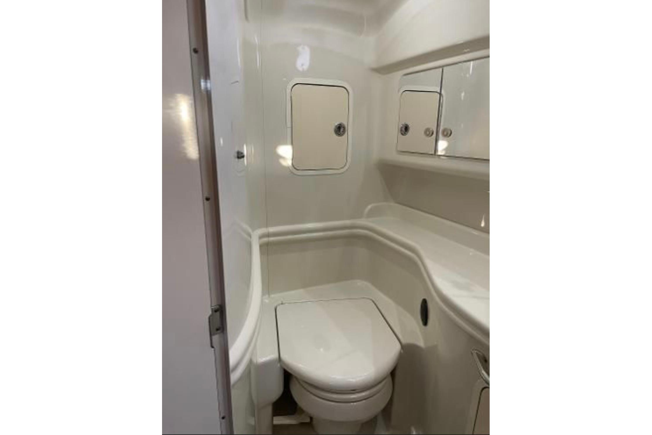 2006 Sea Ray Sundancer 320 boat bathroom with white fixtures and storage cabinets.
