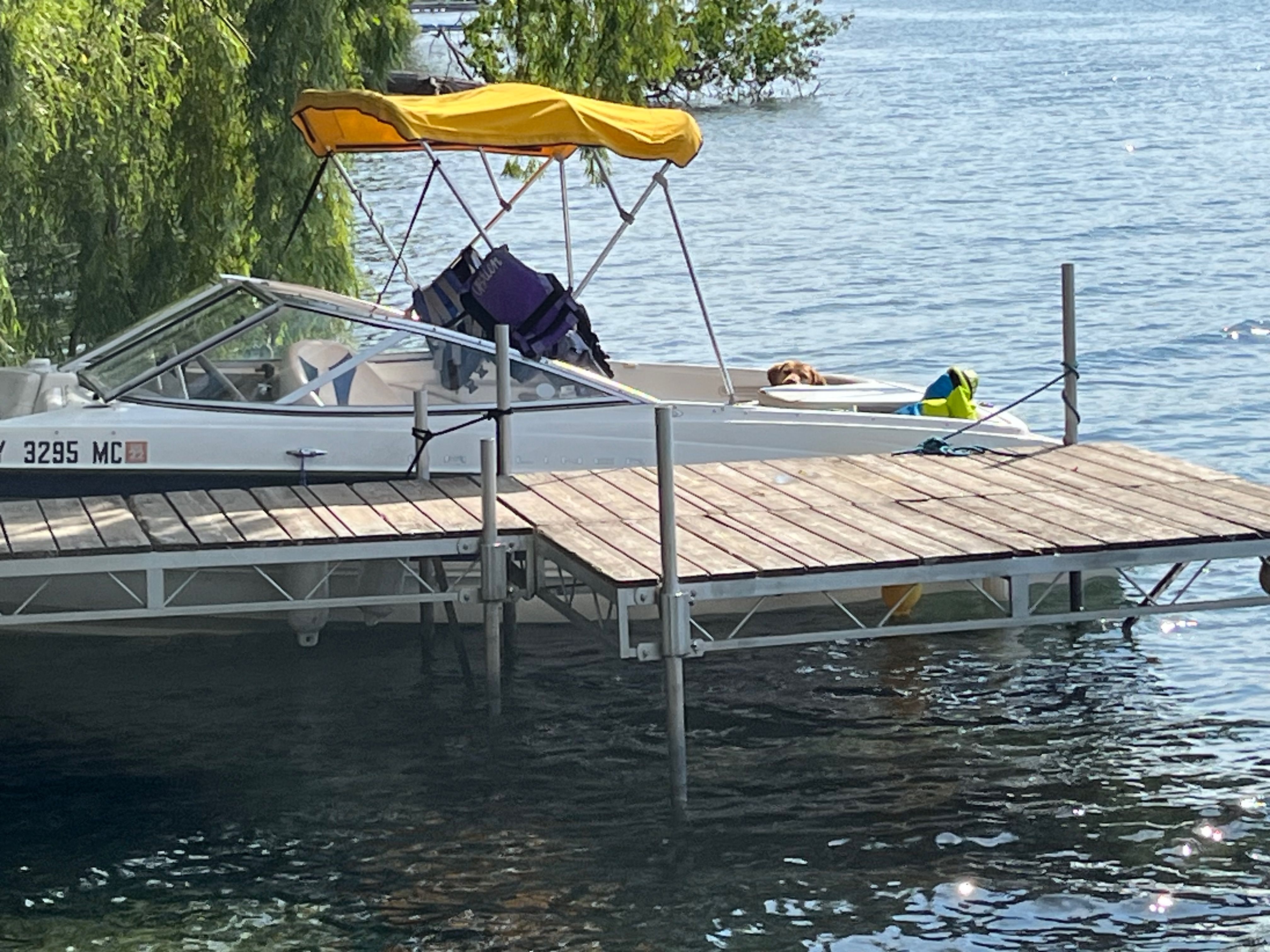 A 2005 Bayliner 205BR is docked at a wooden pier. It features a yellow sunshade.