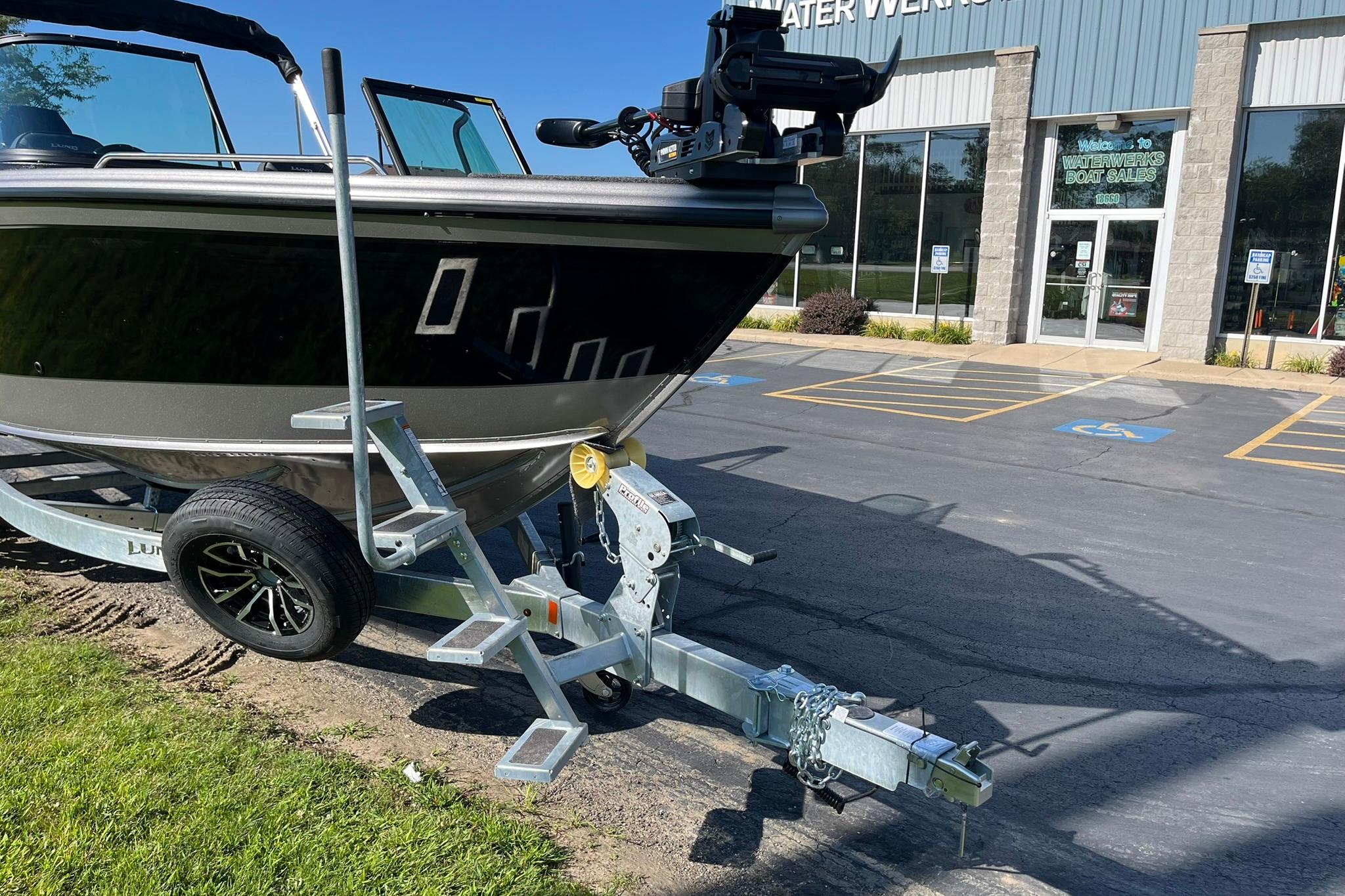 2026 Lund 2275 Baron boat on trailer outside dealership, sunny day.