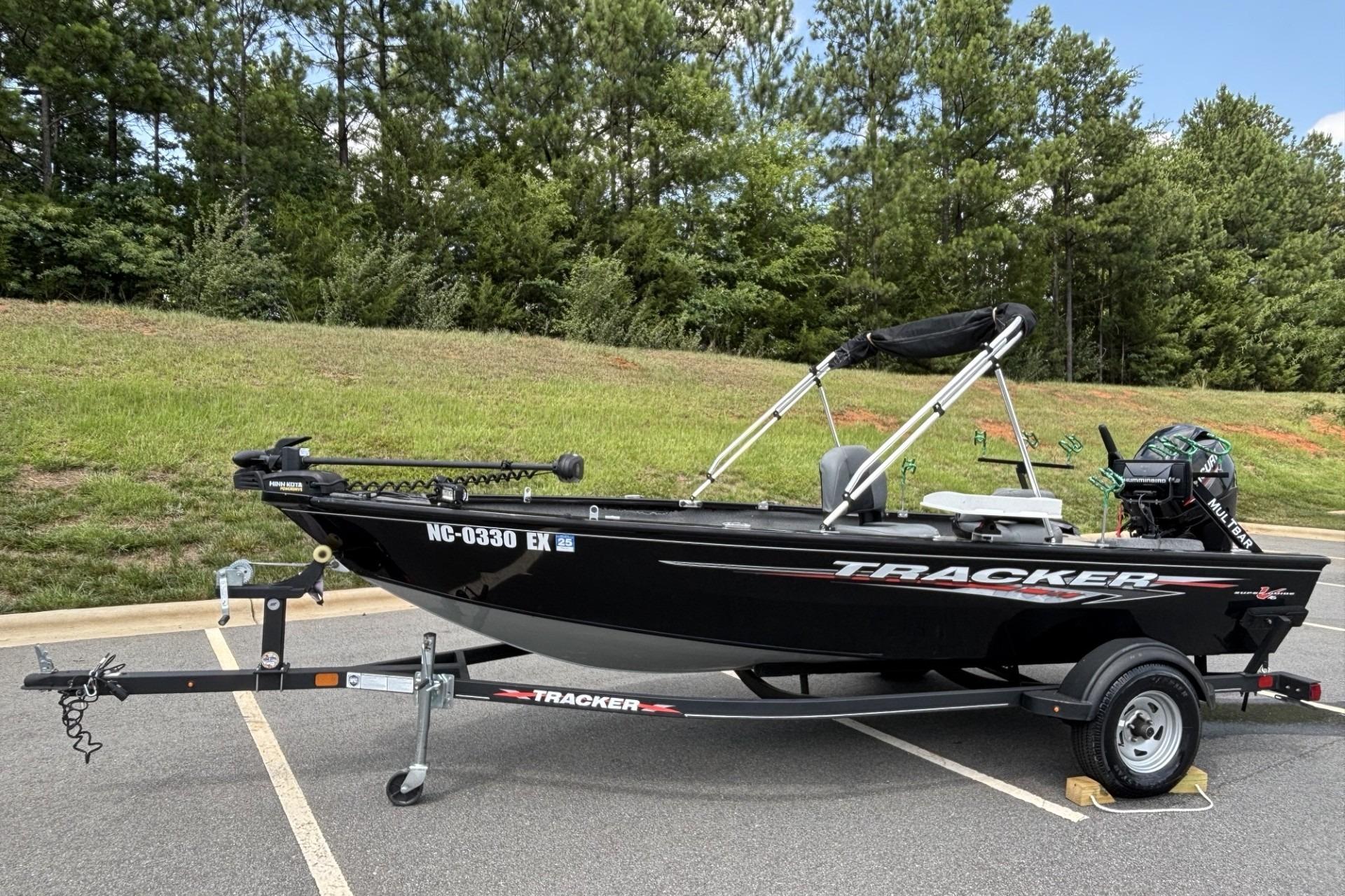 2022 Tracker Super Guide V-16 T fishing boat on trailer in parking lot.
