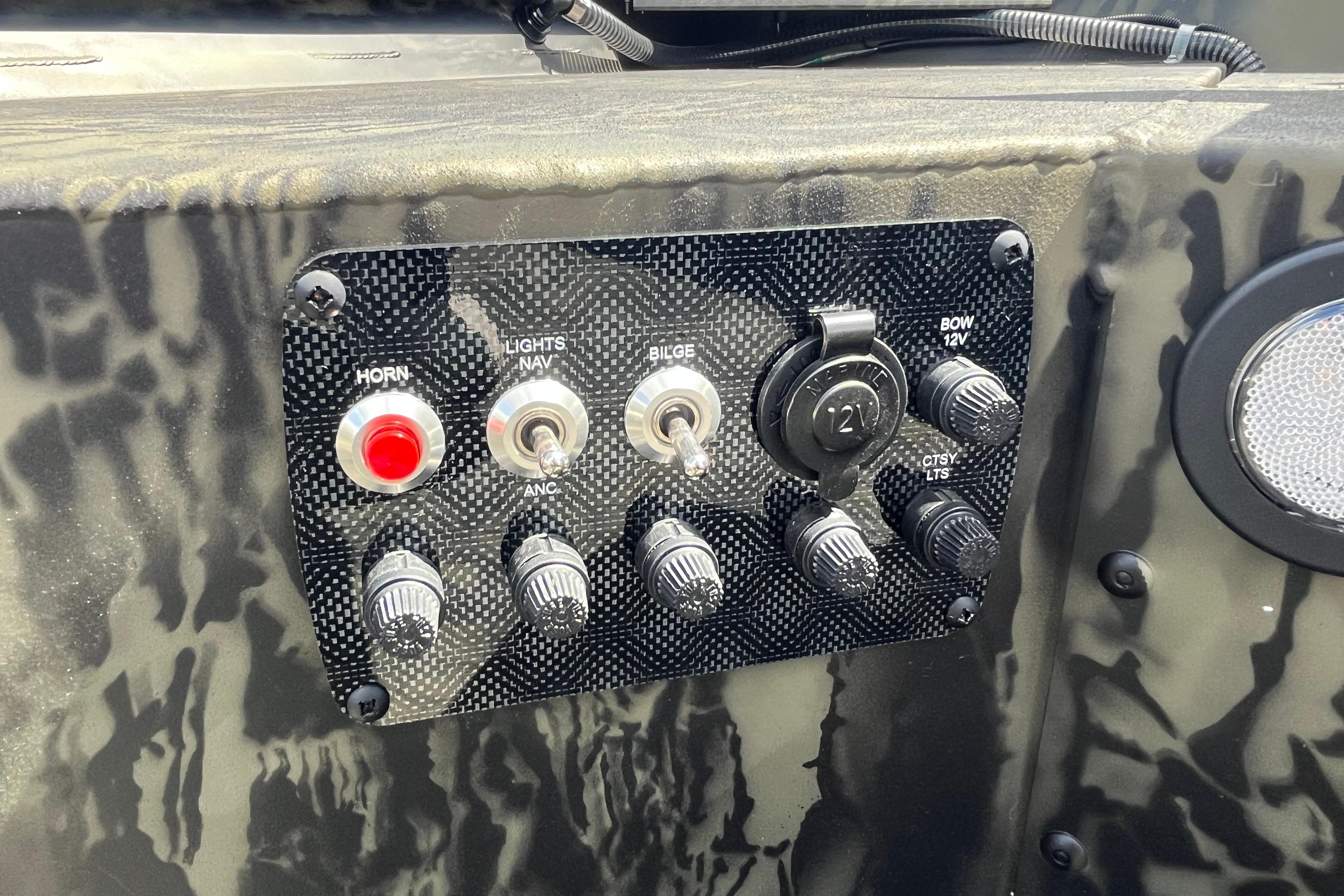 Control panel of 2026 Tracker Grizzly 1654 T Sportsman boat with switches and knobs.