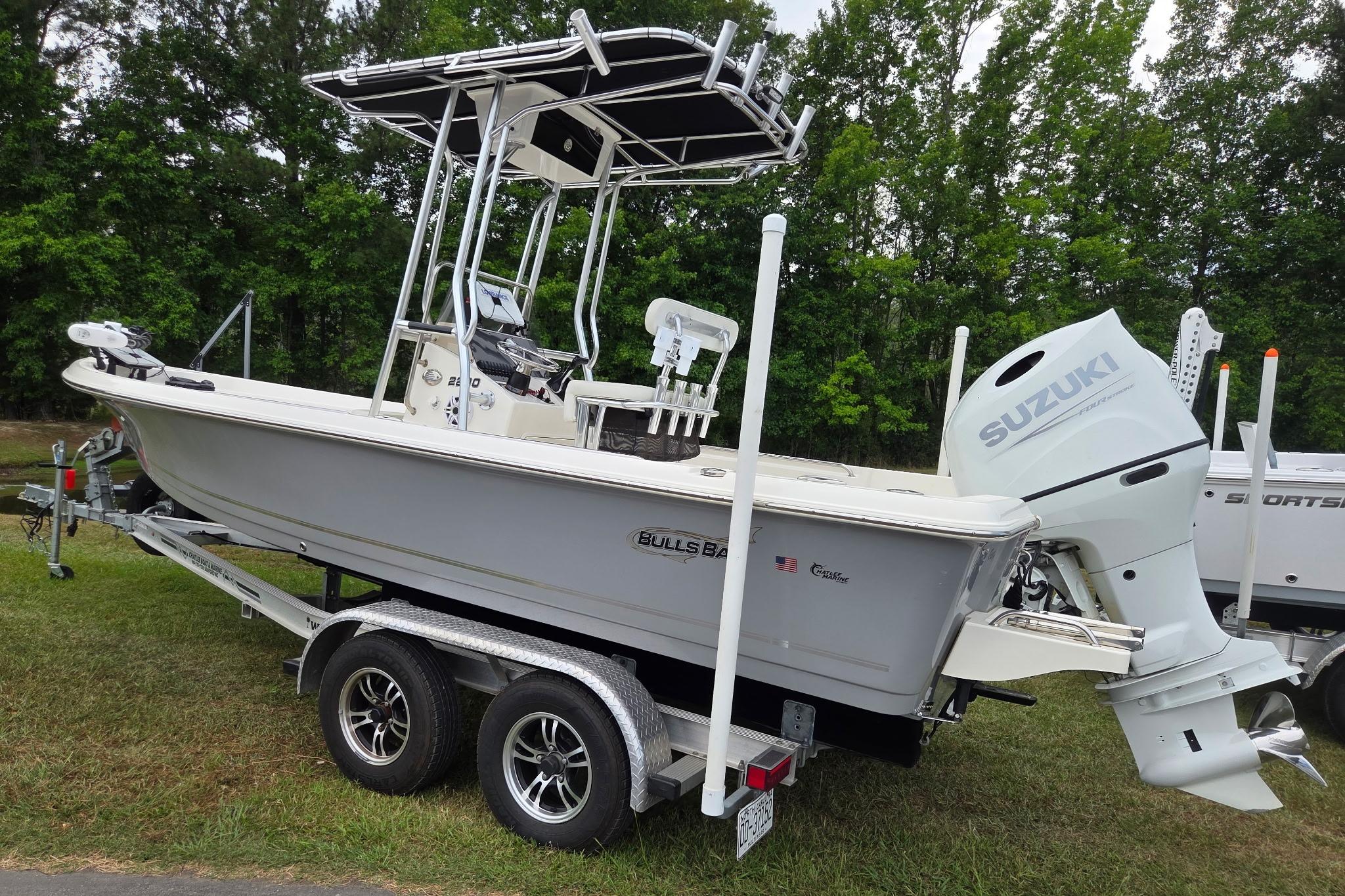 2023 Bulls Bay 2200 boat with Suzuki engine on trailer, parked on grass.