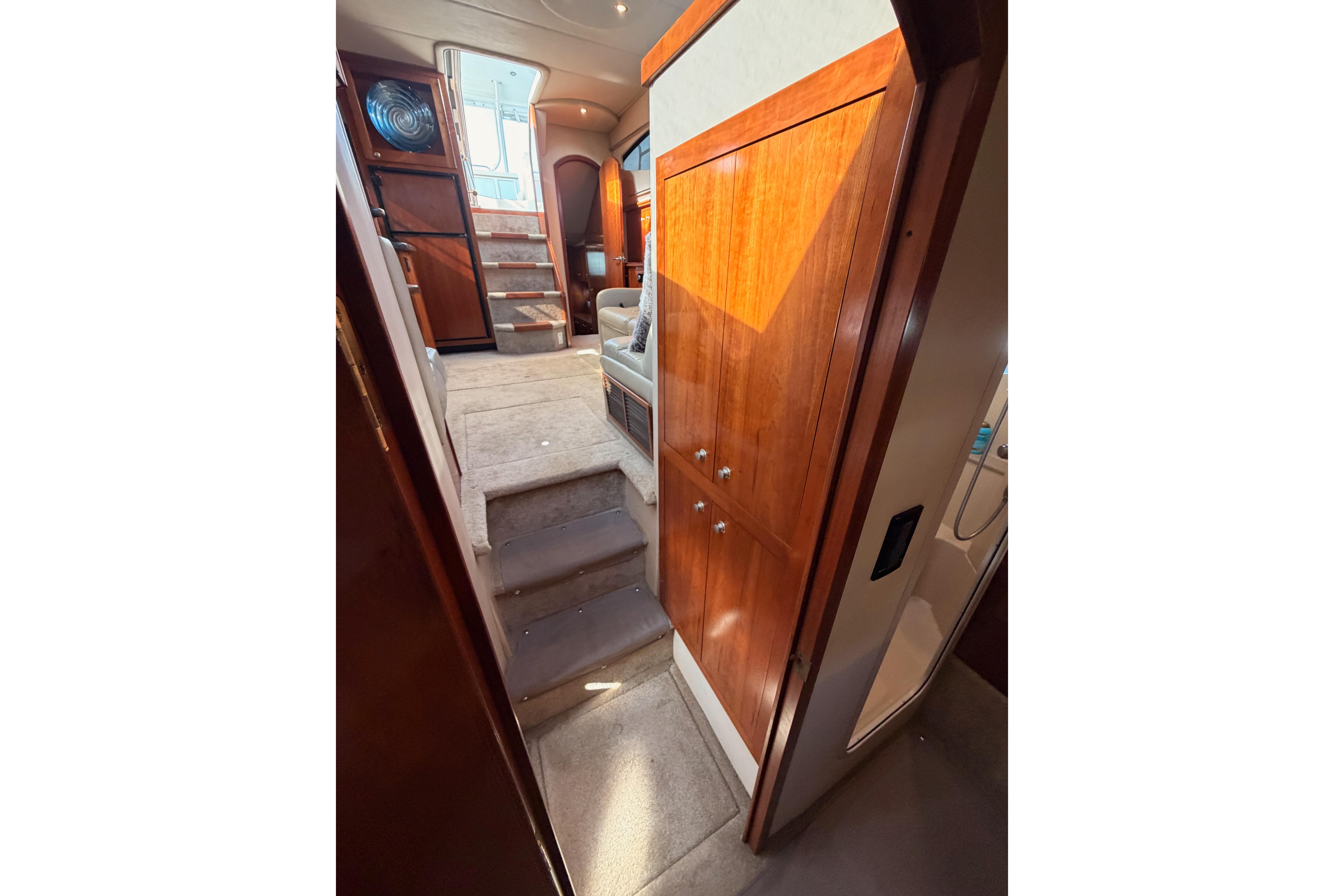 Interior view of 2005 Cruisers Yachts 405 Express Motoryacht with wooden cabinetry and carpeted stairs.