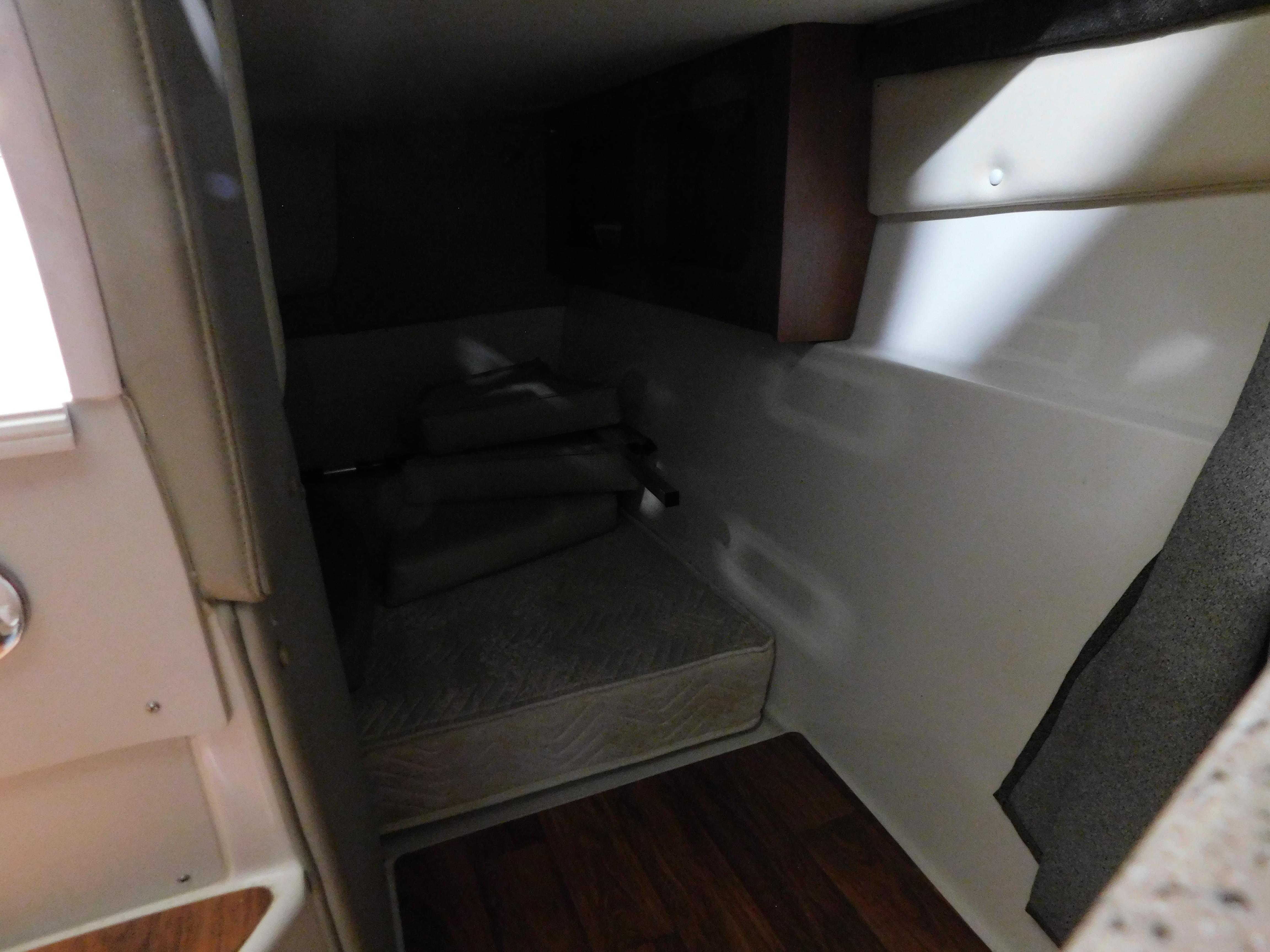 2015 Stingray 250 CS cabin interior with bed and wooden flooring.