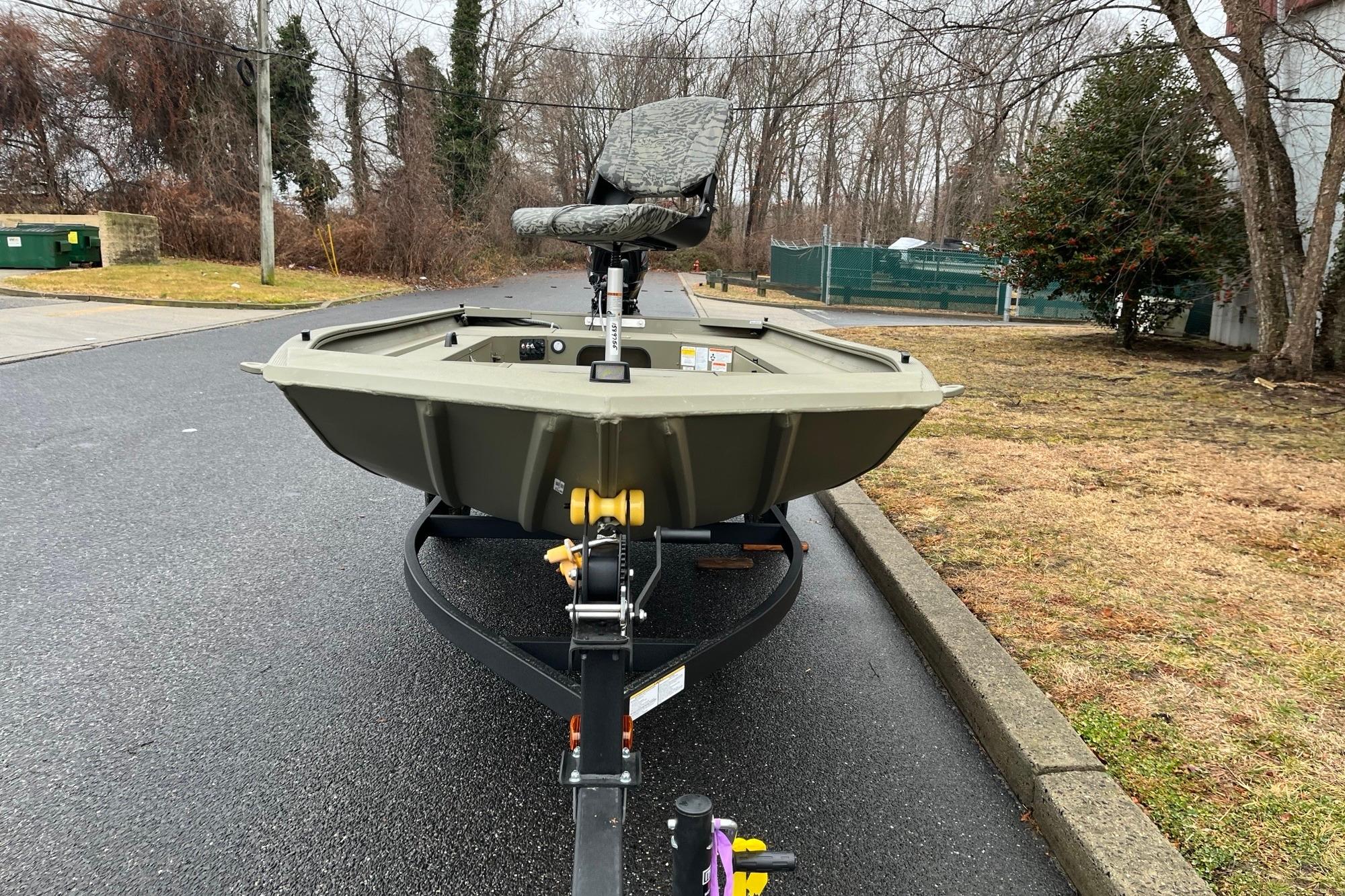 2026 Tracker Grizzly 1654 T Sportsman boat on trailer, parked on wet pavement.