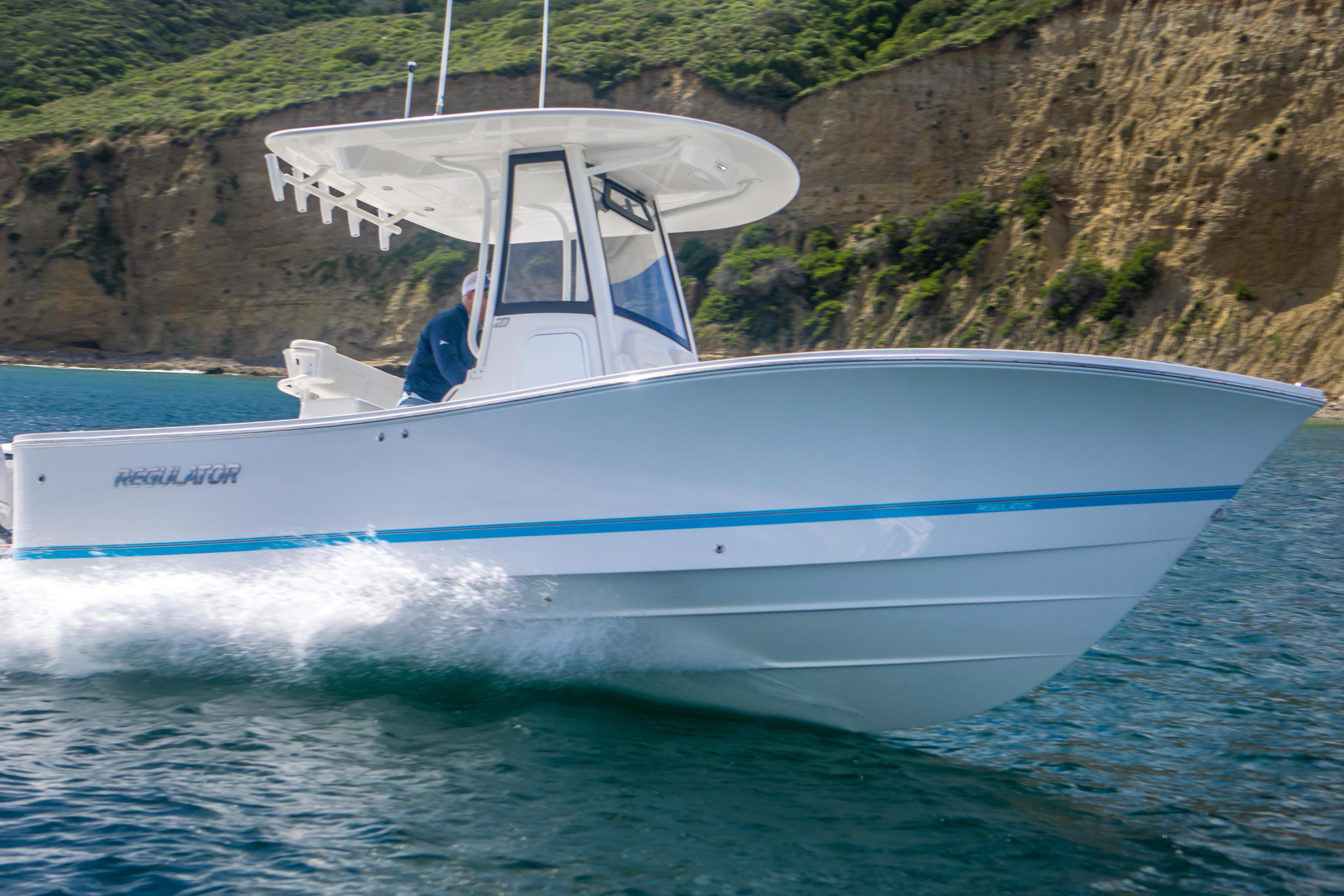 2026 Regulator 23 boat cruising on water near rocky coastline.