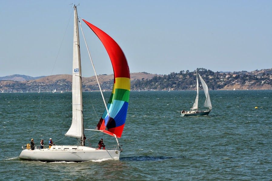 Beneteau First 40.7 sailboat with colorful spinnaker on the water.