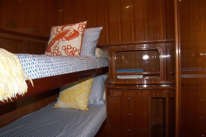 Cozy cabin interior of 2004 Hampton F/B Cruiser with wooden bunk beds and colorful pillows.