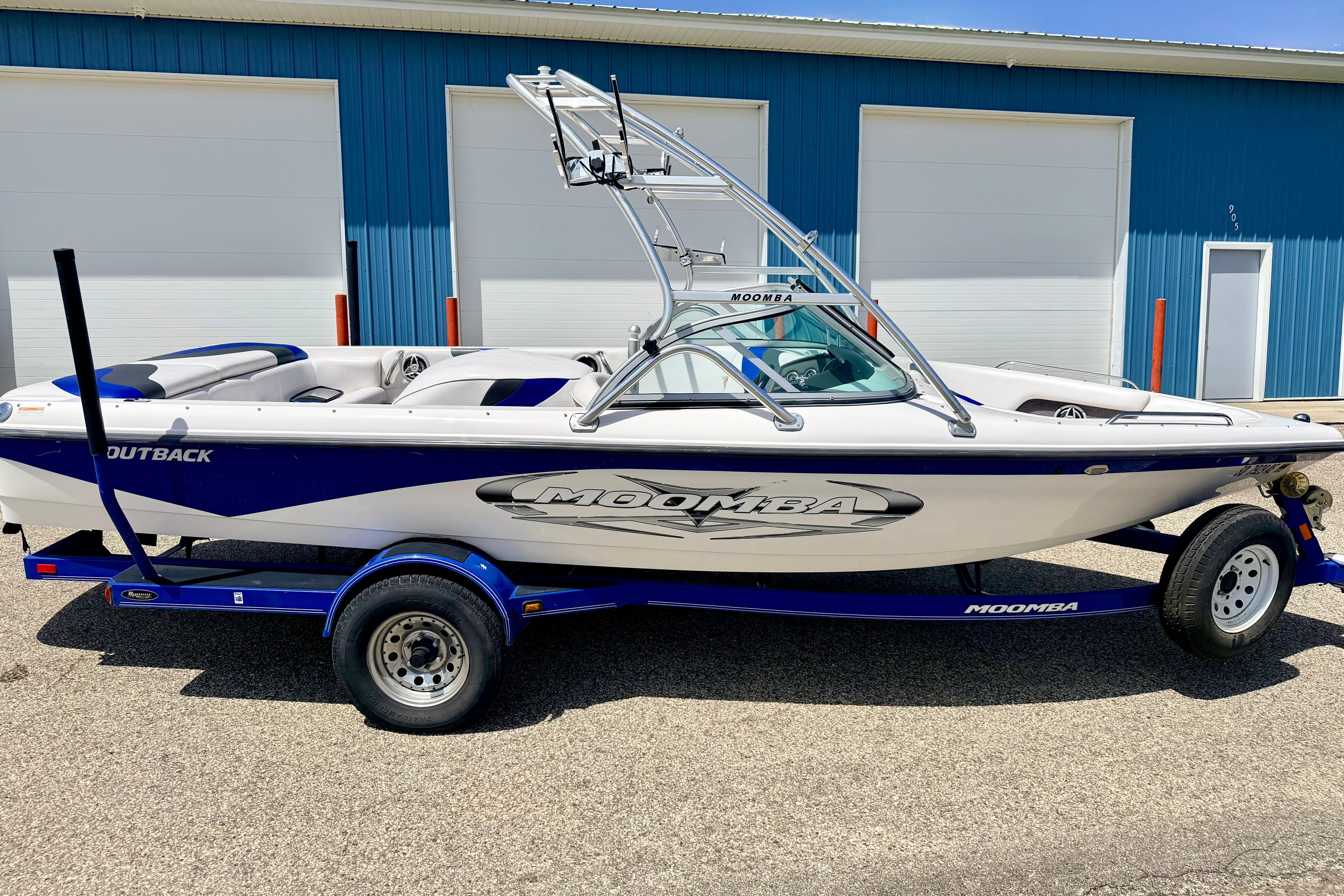 2008 Moomba Outback V boat on trailer, parked outside blue building.