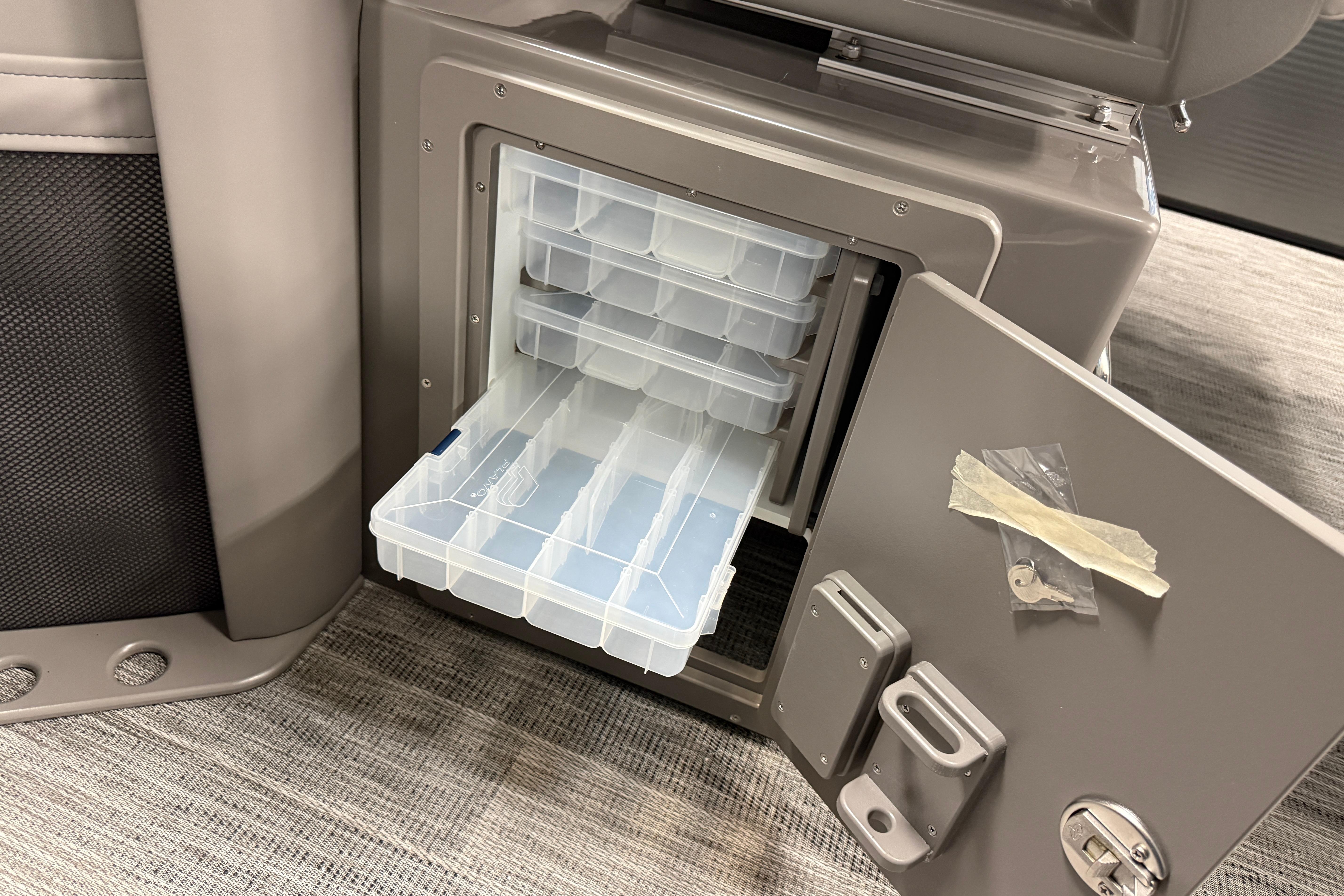 Open storage compartment in 2026 Qwest M-Class 22 Pro Sport boat, featuring organized plastic trays.