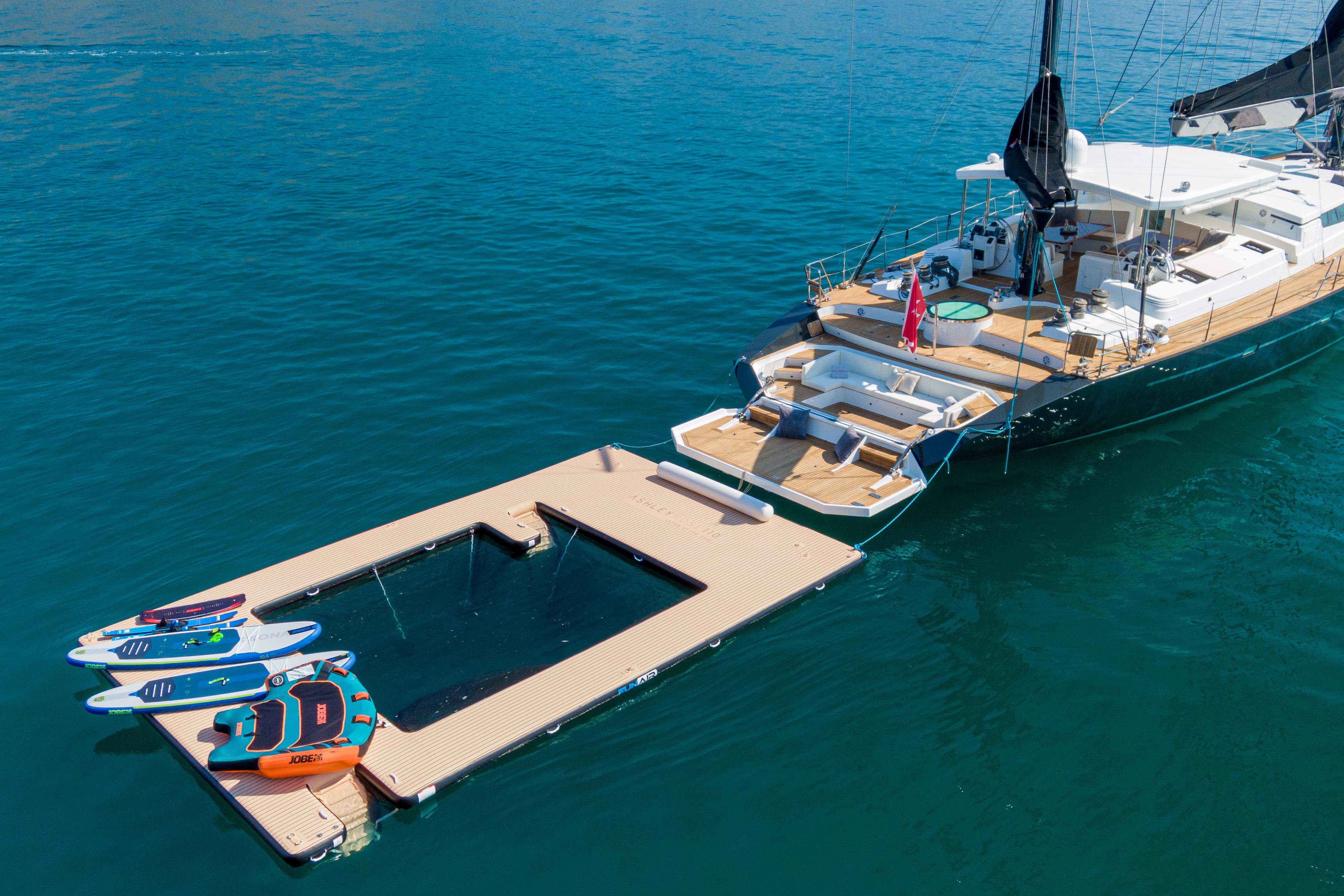 Luxury yacht with floating dock and water sports equipment on a calm sea.