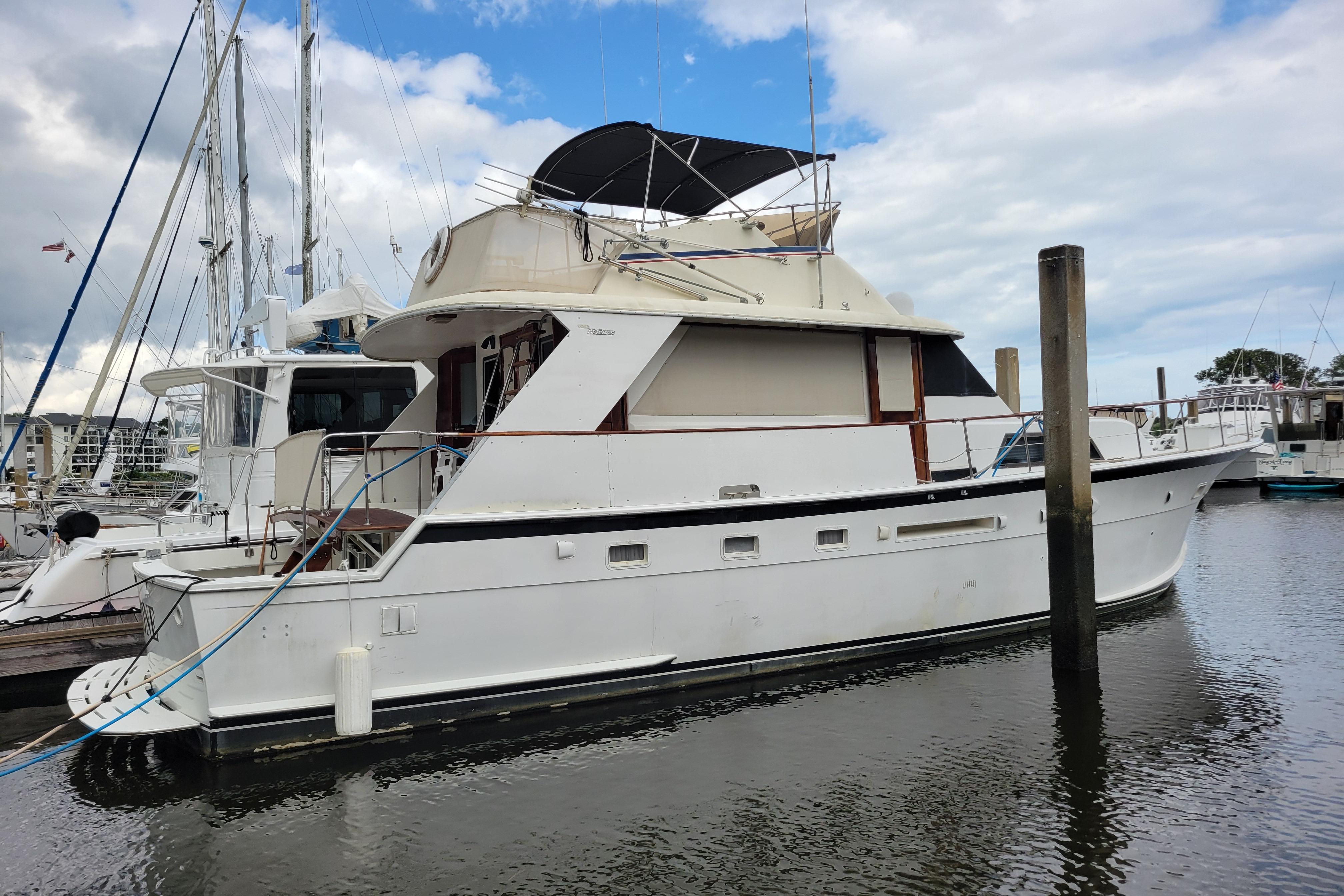 1980 Hatteras 53 Yacht Fisherman docked at marina under cloudy sky.