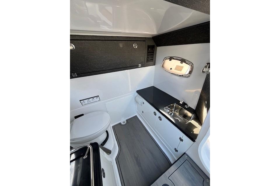Interior of 2026 Monterey Elite 27 SD boat featuring a compact bathroom with sink and toilet.