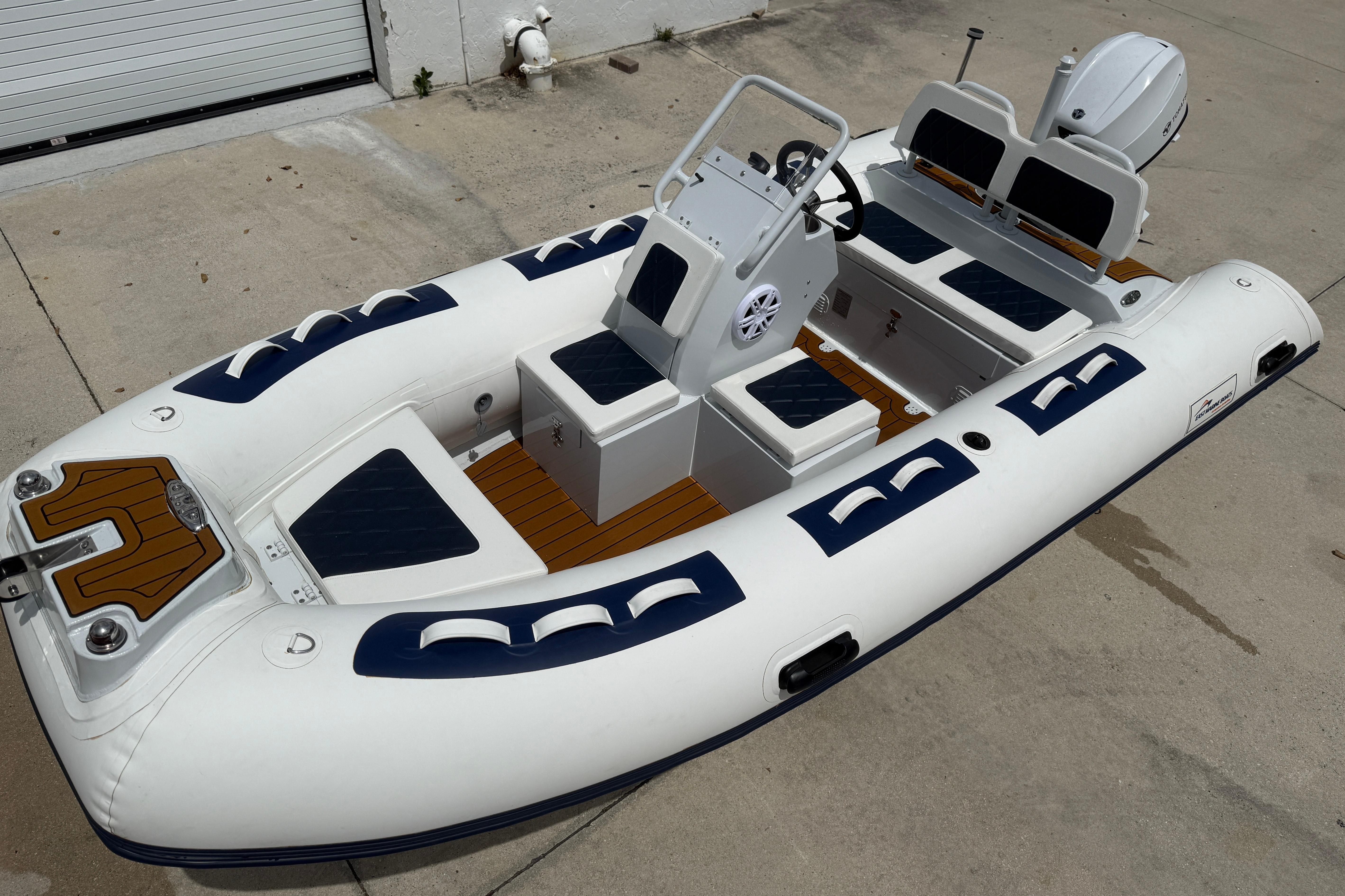 2026 East Marine 420 LUXURY inflatable boat with seating and steering console on concrete surface.