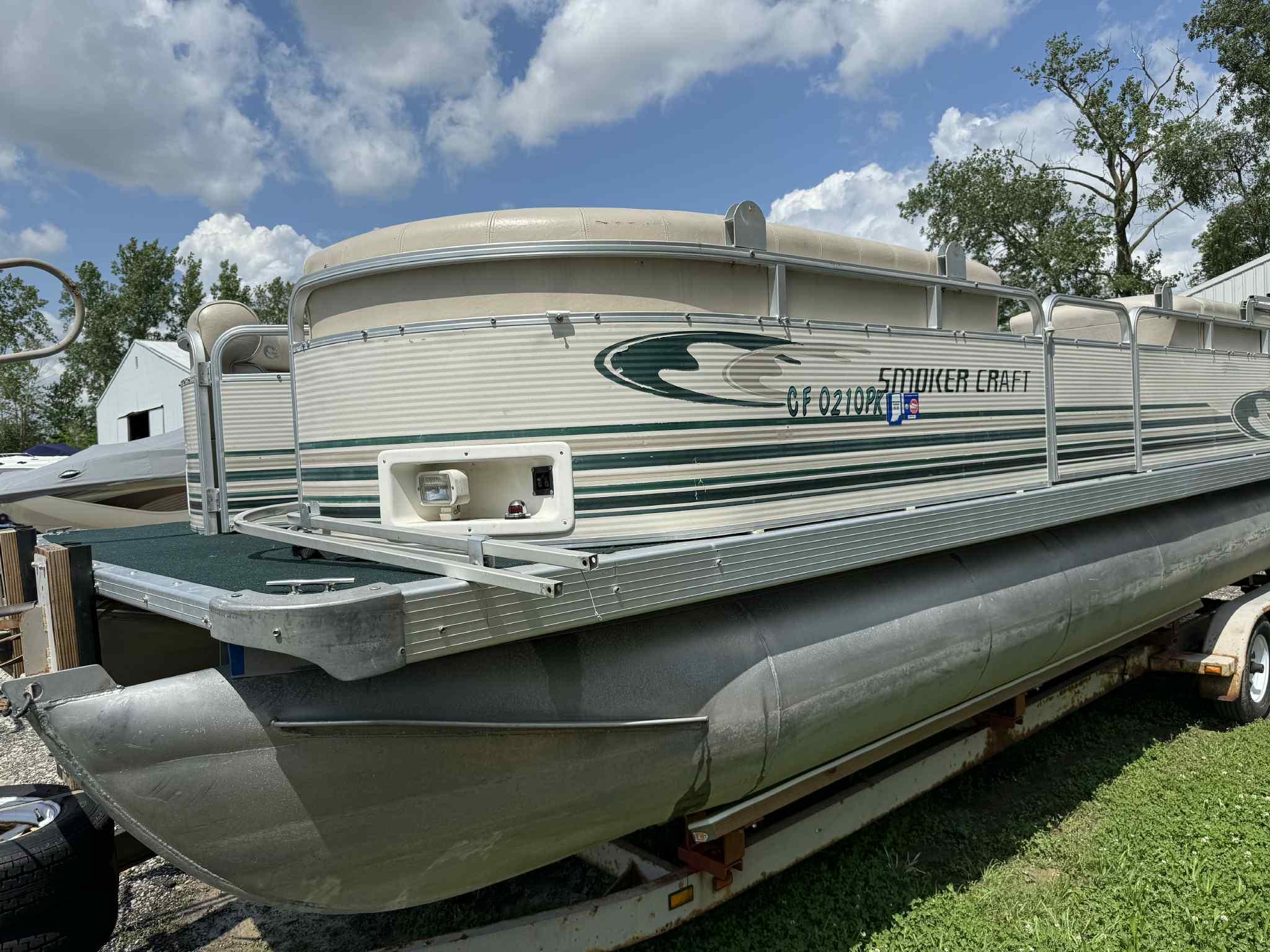 1999 Smoker Craft 8526 Pleasure Isle I/O pontoon boat on trailer, under a blue sky.