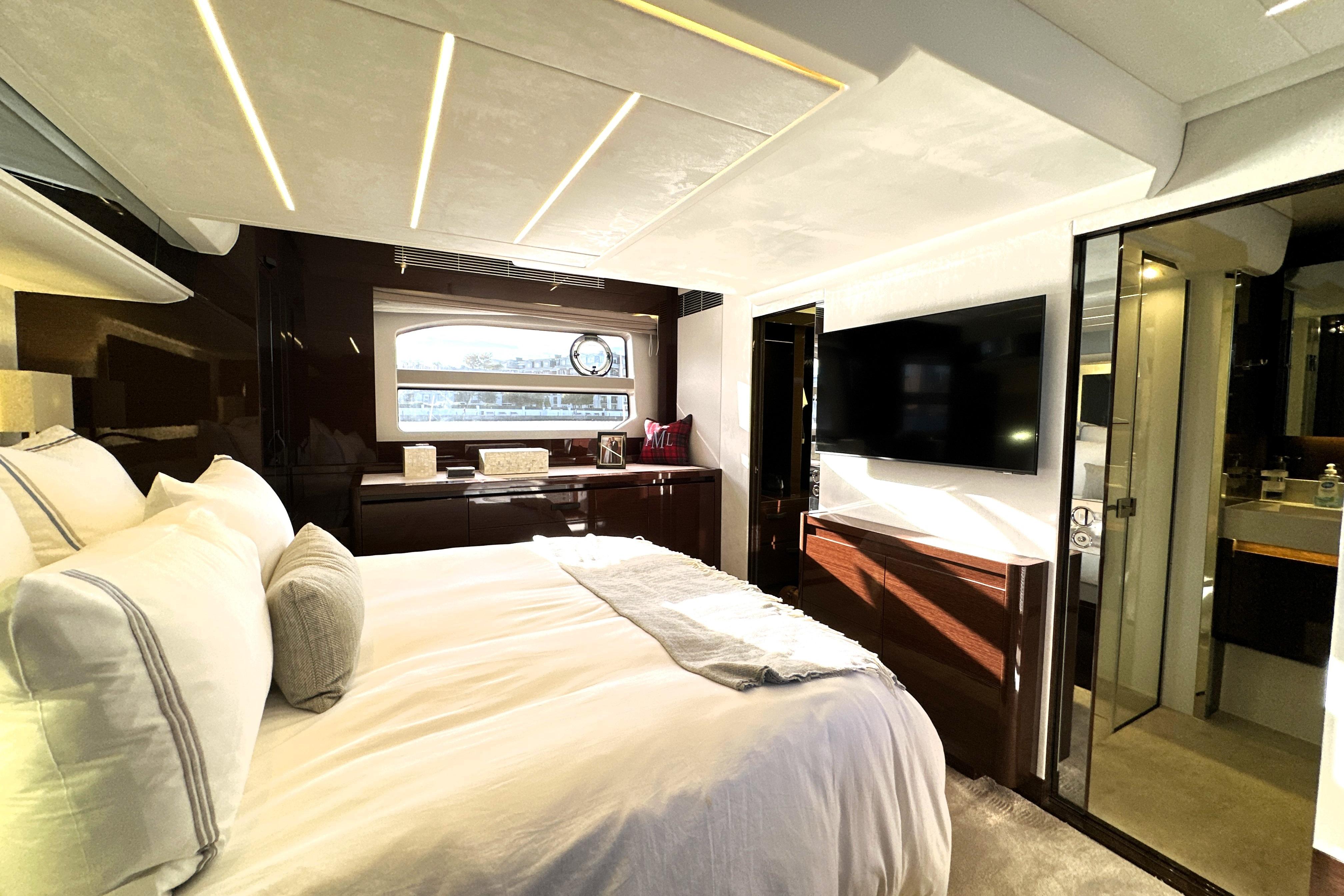 Luxurious bedroom interior of 2023 Prestige 590 yacht with modern decor and large TV.