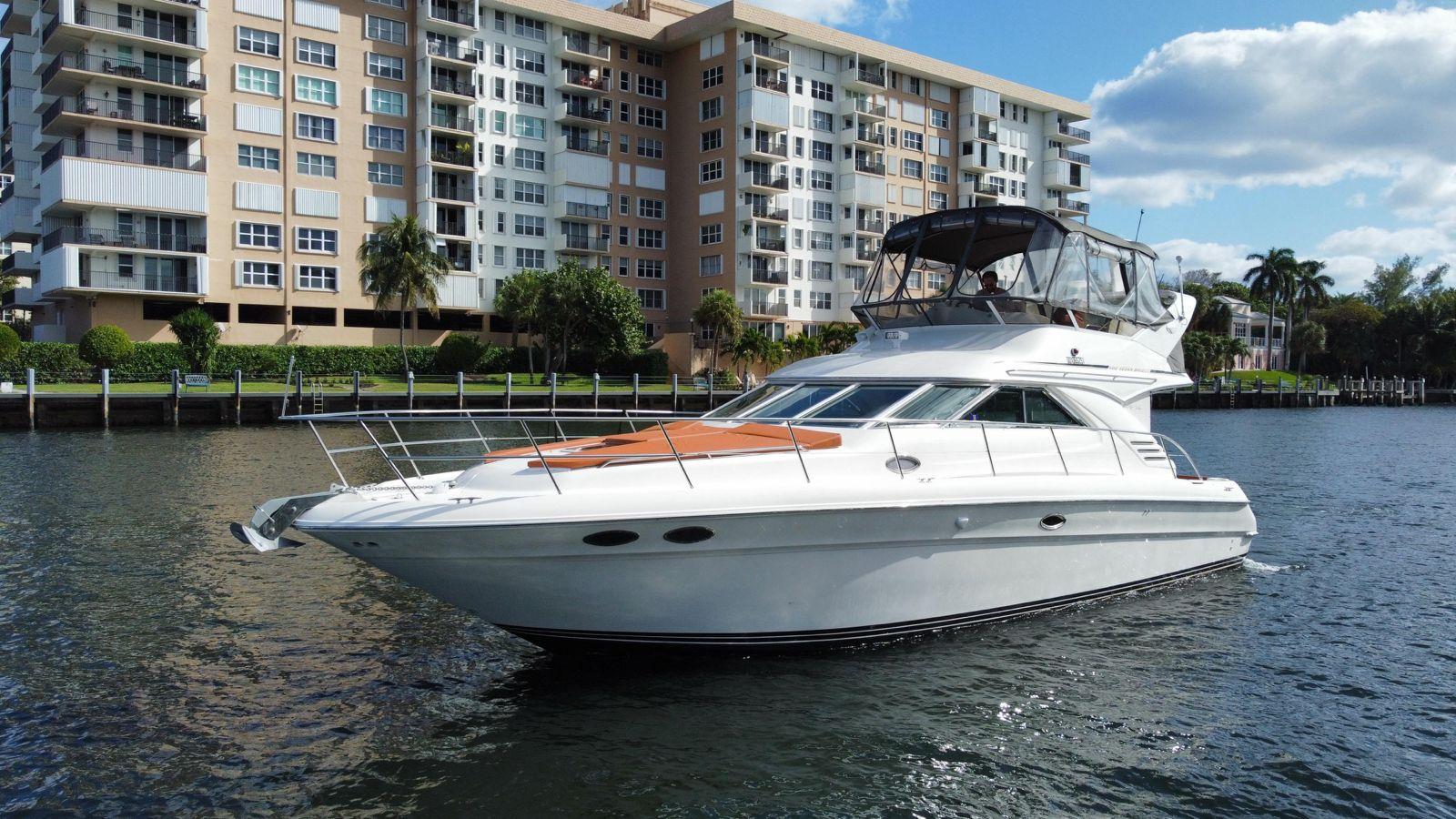 1997 Sea Ray 400 Sedan Bridge yacht cruising near waterfront apartments.
